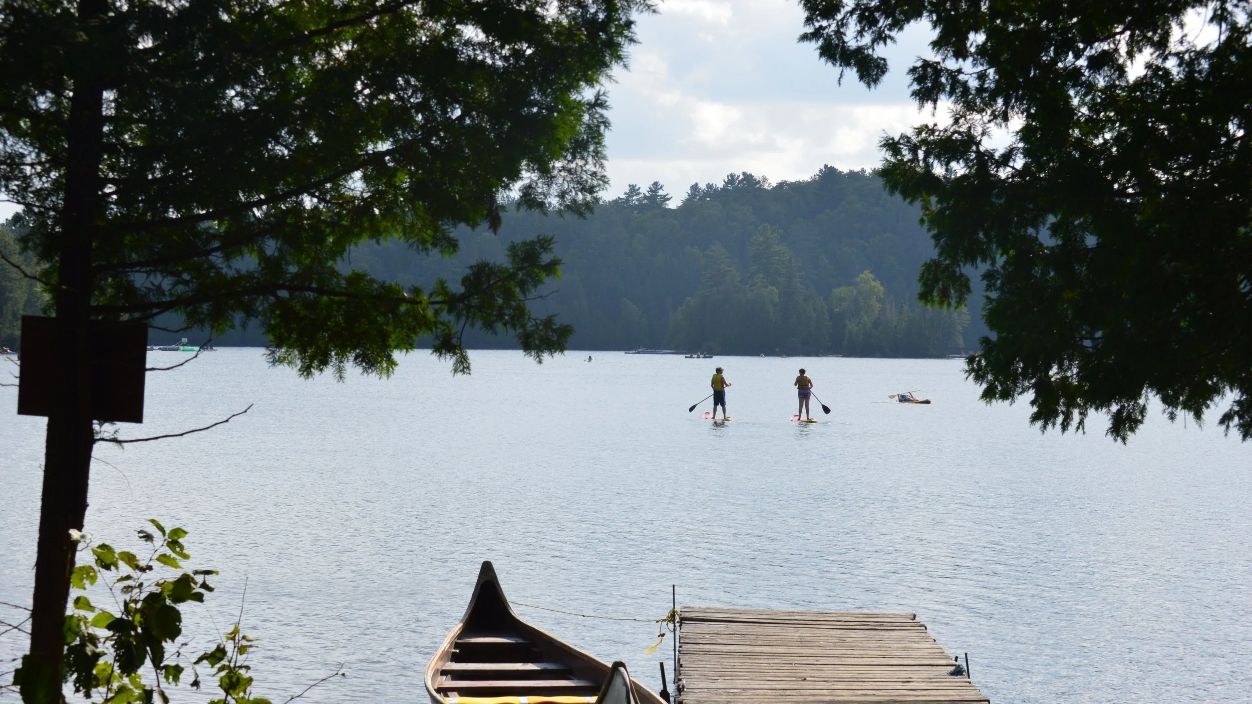 People paddleboarding on a lake surrounded at Hidden Acres camp.