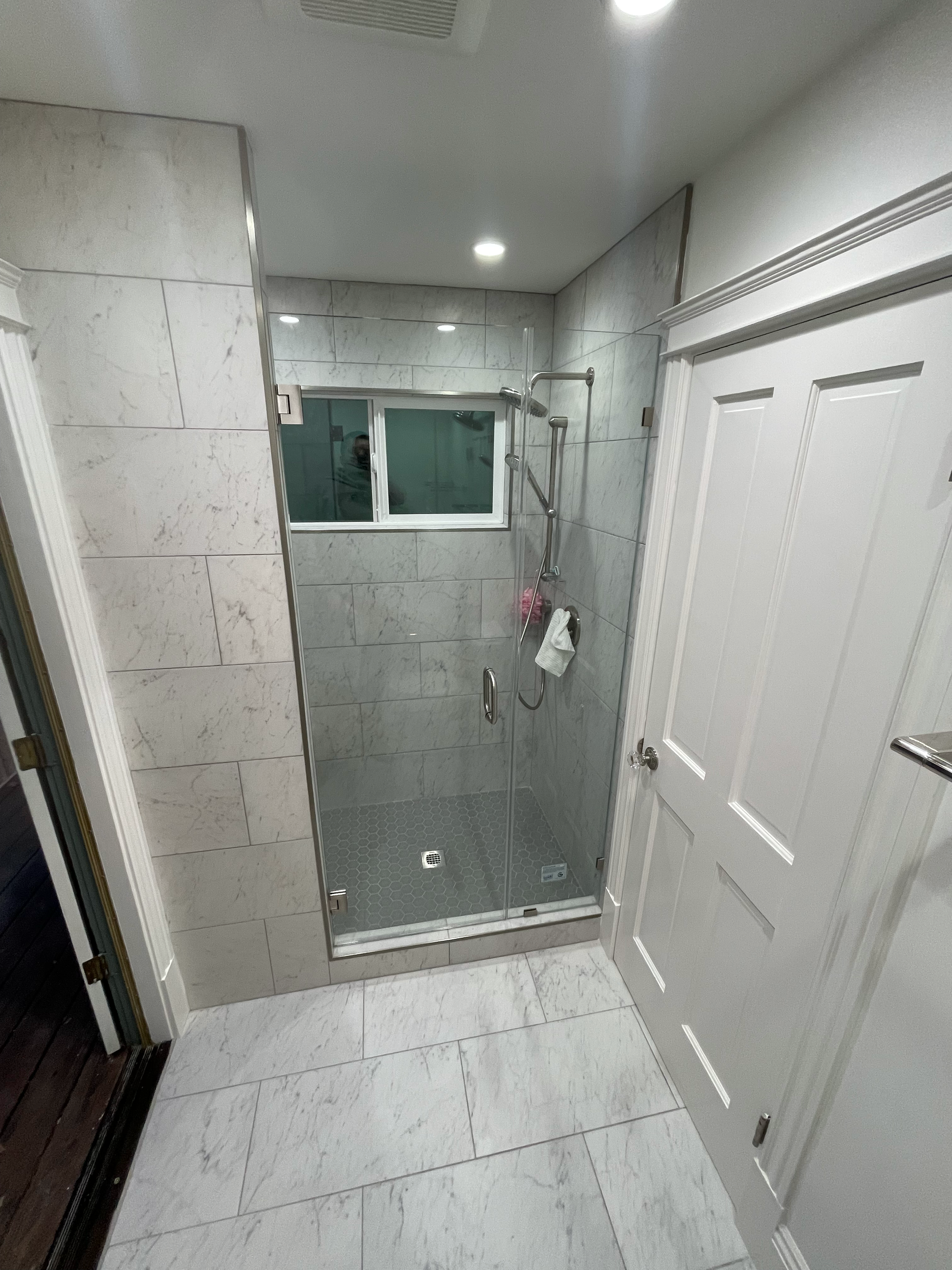 Modern bathroom with white marble tiles and glass shower enclosure