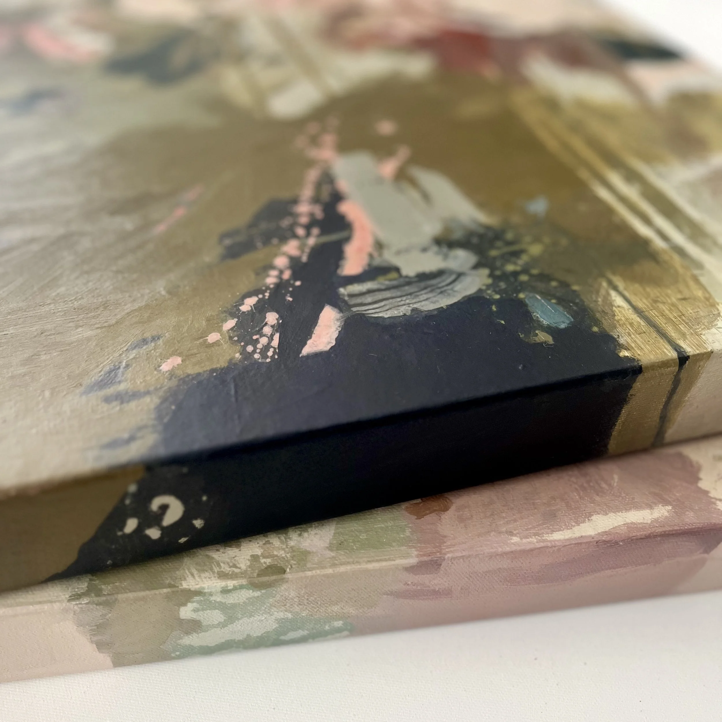 Close-up of an abstract painted artwork on a canvas featuring blue, pink, green and beige colors with textured brushstrokes.