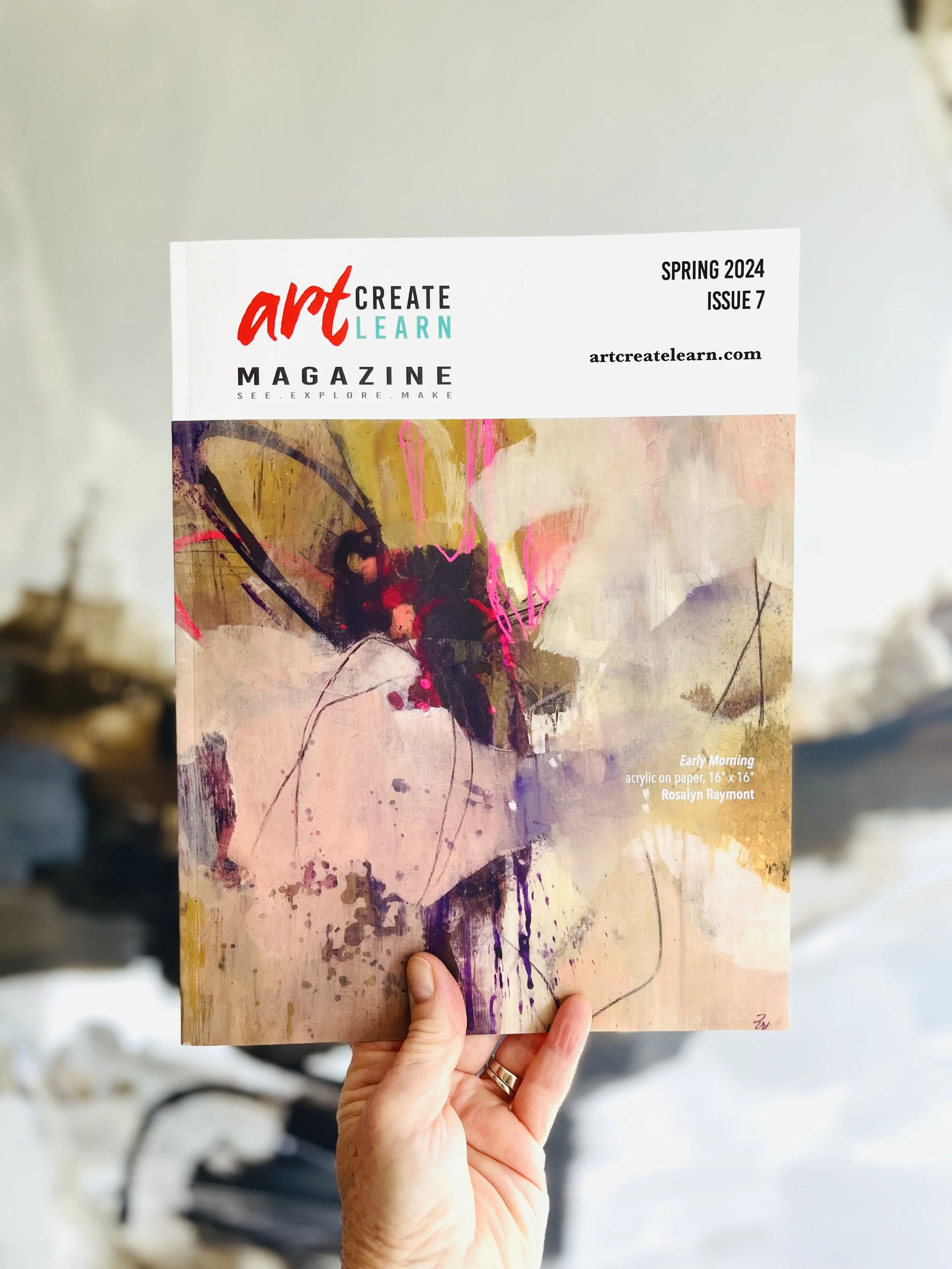 Hand holding the spring 2024 issue of Art Create Learn Magazine with an abstract acrylic painting on the cover featuring pink, purple, and black splashes and strokes