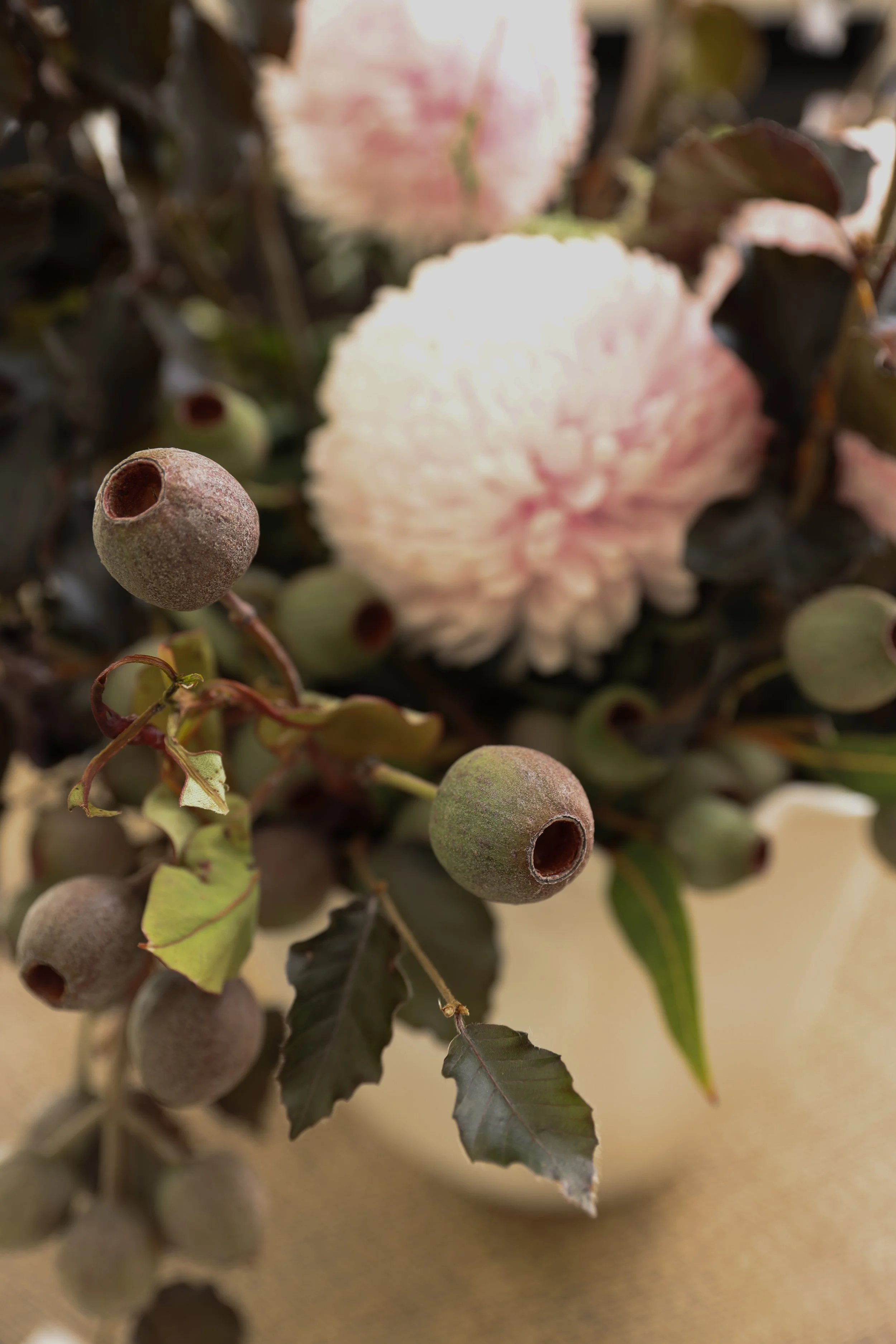 Close-up of a bouquet with pink and white flowers, green leaves, and small round berries.