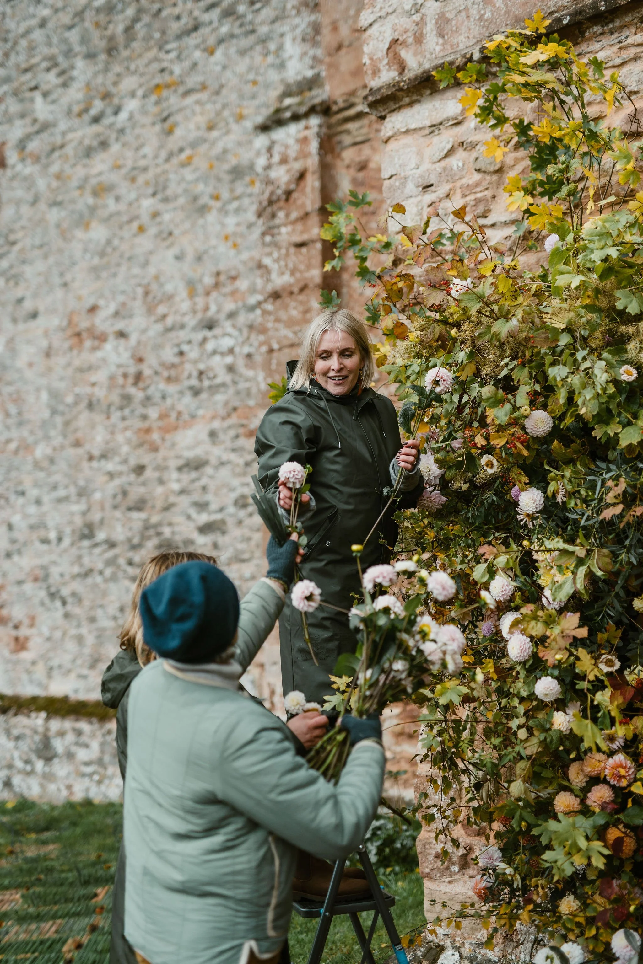 Florists create a floral arch outside a church for a wedding.