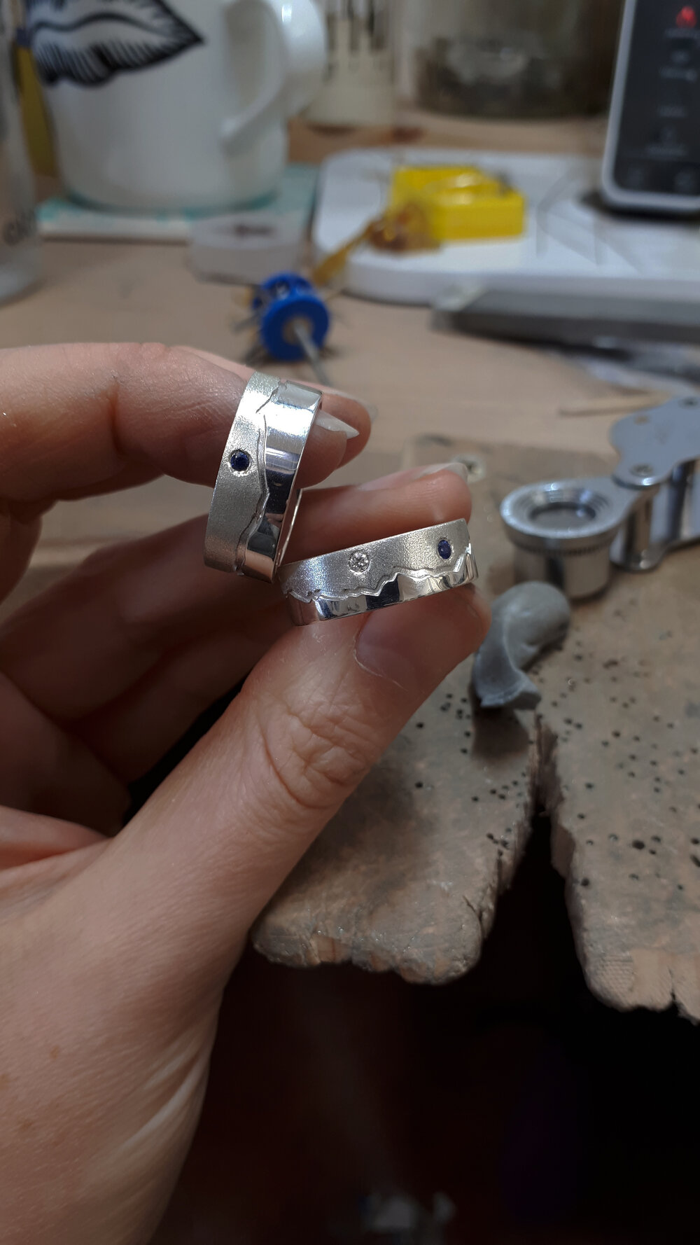 jen-holds-two-handmade-wedding-rings-at-her-bench.jpg