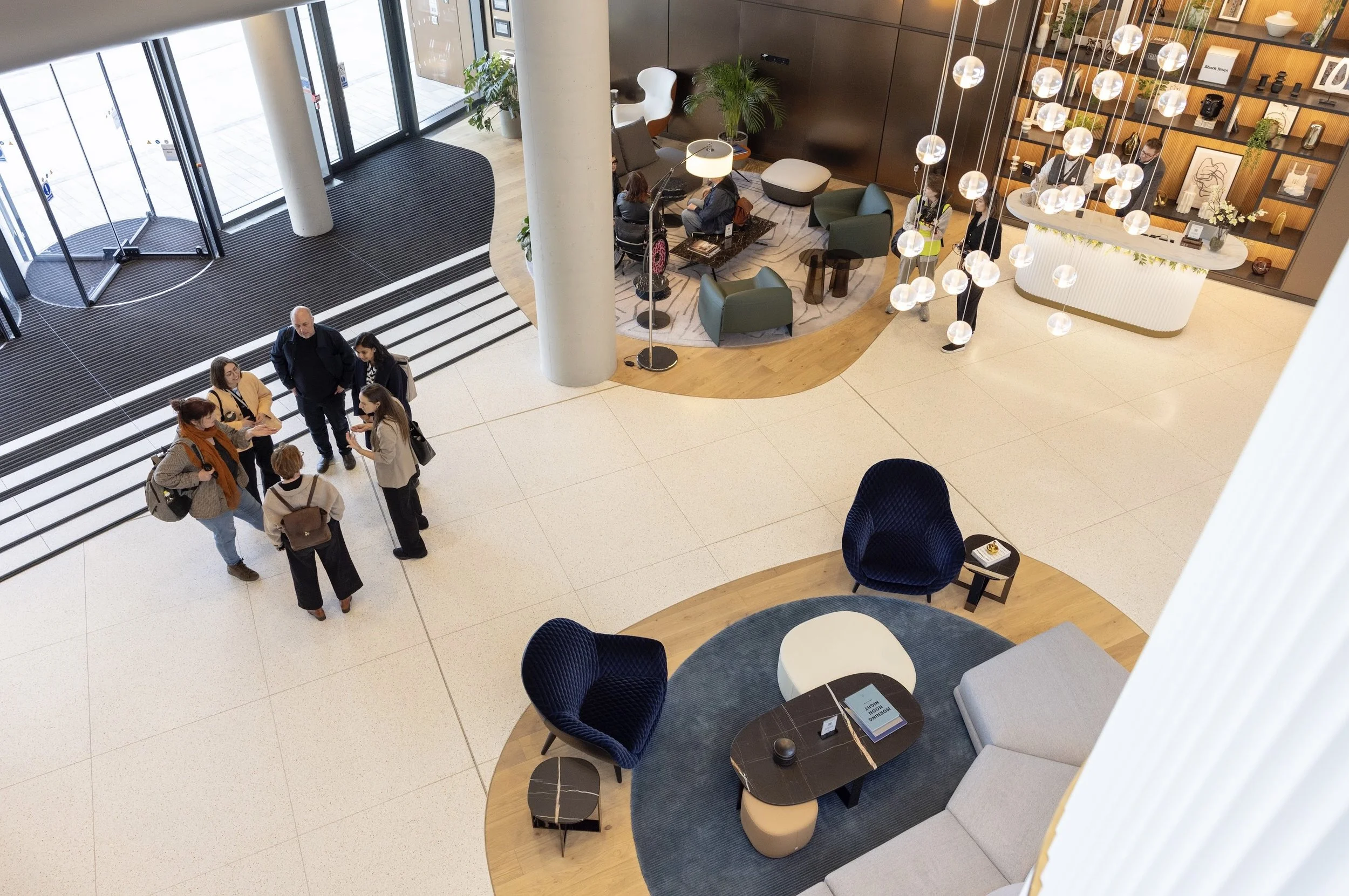 Birds eye photo of a mixed group of six people talking in a lobby space.