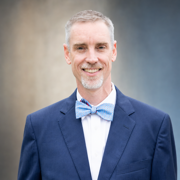 Ben Smith smiling, wearing a navy suit and bow tie