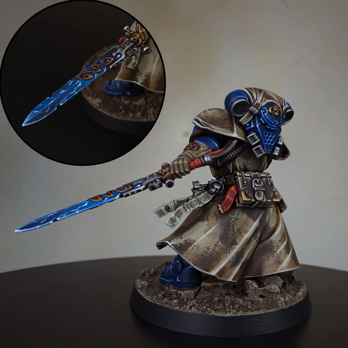 A detailed miniature figure of a sci-fi soldier in armor, holding a blue lightning-themed sword, standing on a textured base against a plain background. An inset shows a close-up of the sword and part of the figure's hand.
