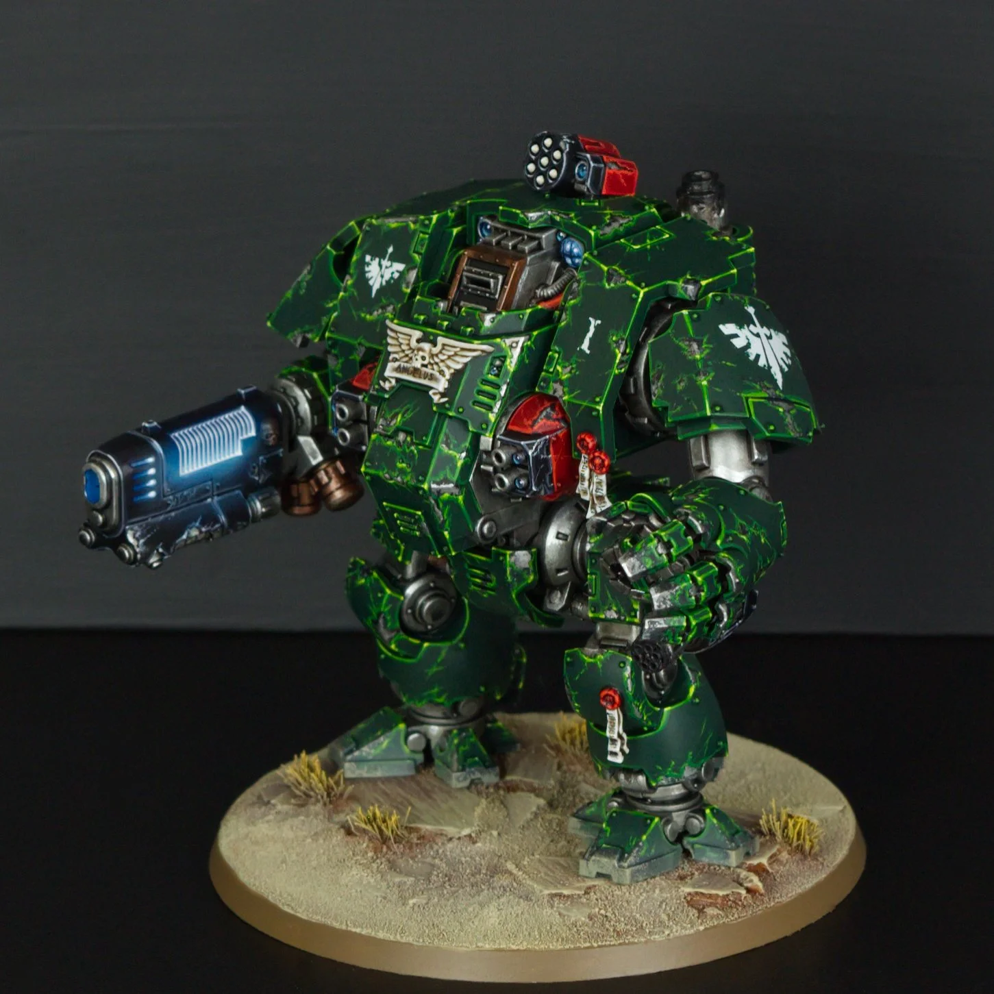 Model of a green Warhammer 40k Space Marine with a large gun, standing on a desert-themed base.