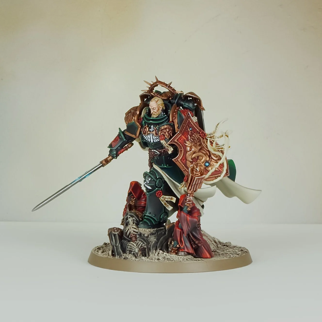 Painted miniature figurine of a medieval knight with a shield and sword, standing on a textured base.