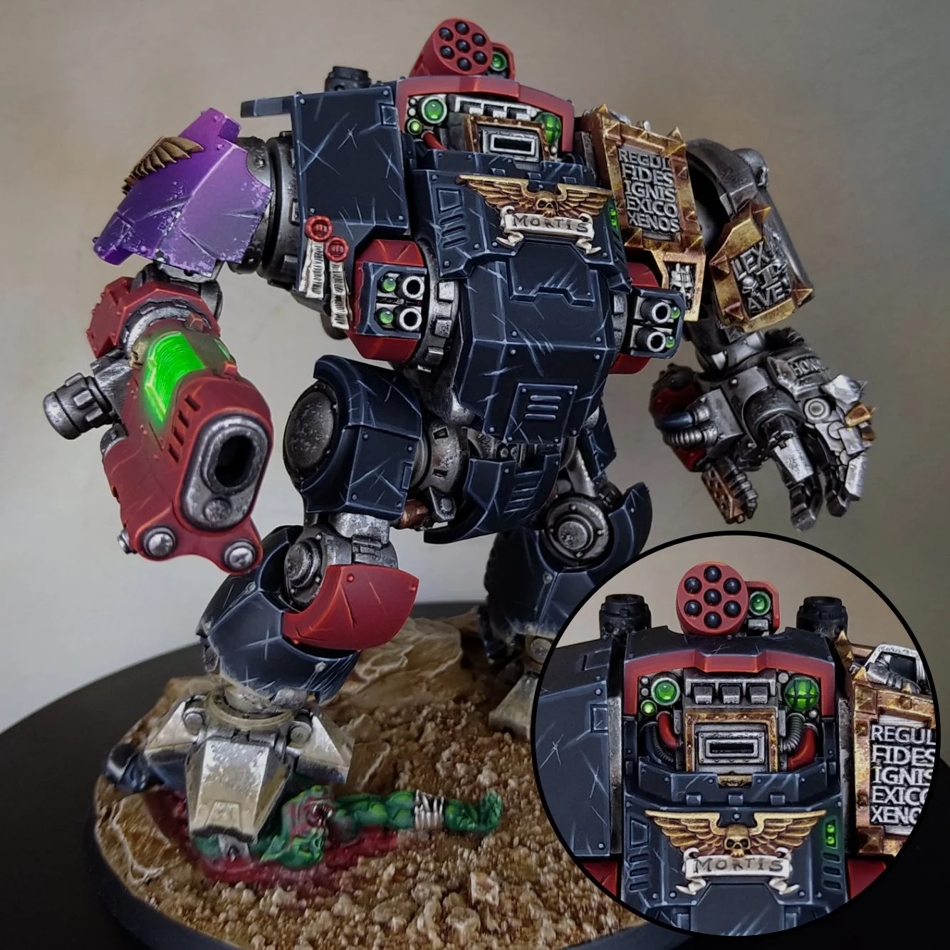 A highly detailed model of a sci-fi battle mech with a black, red, and purple color scheme. It features various decals, armor plates, and weaponry, standing on a textured base. An inset close-up shows the chest area with green lights, wires, and pain