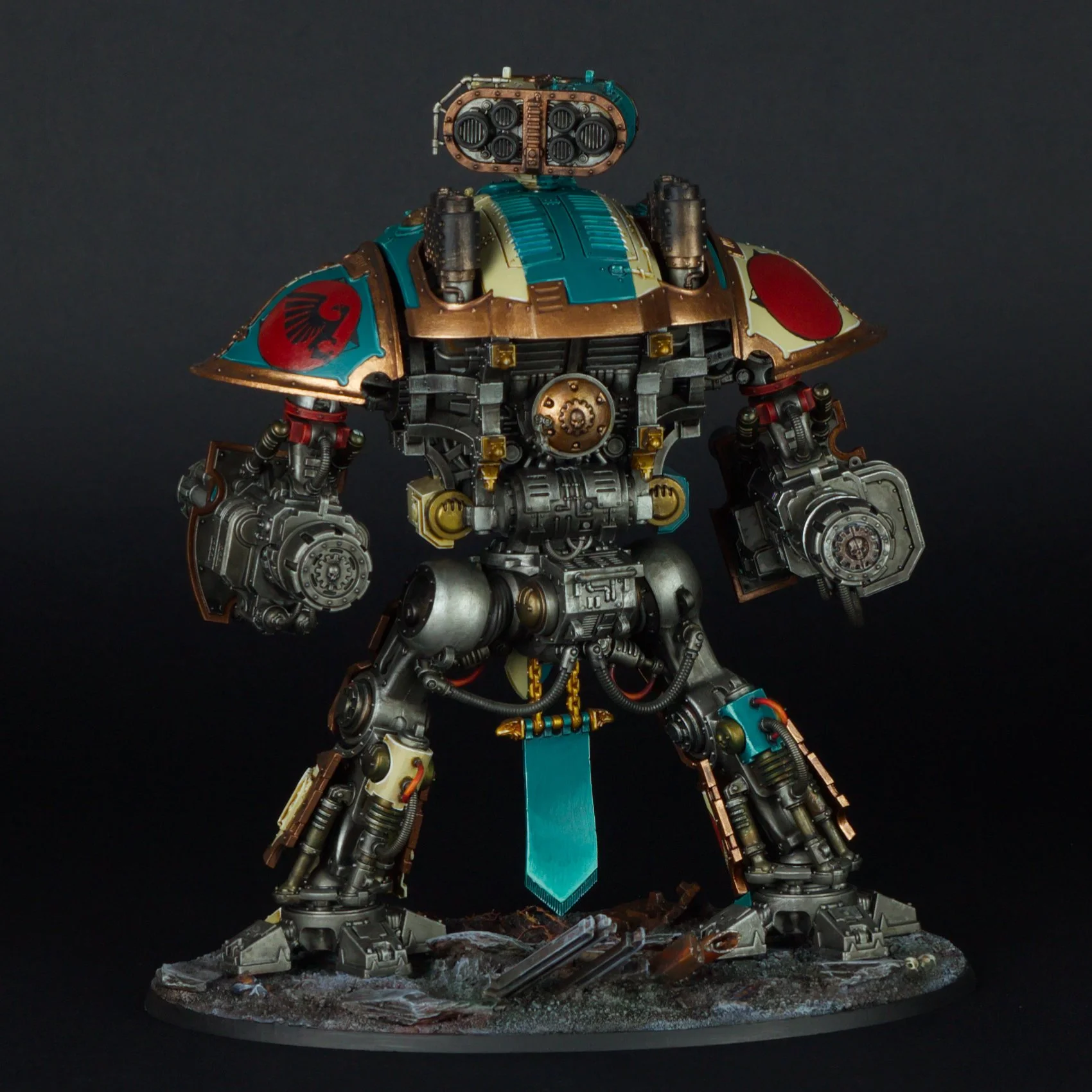 A detailed miniature robot model with a metallic body, blue and gold accents, and a turquoise sword, standing on a rocky base against a dark background.