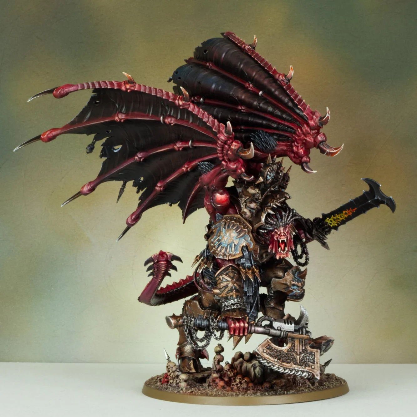 A detailed fantasy figurine of a demon warrior with large bat-like wings, armor, and a sword, standing on a rocky base with skulls.
