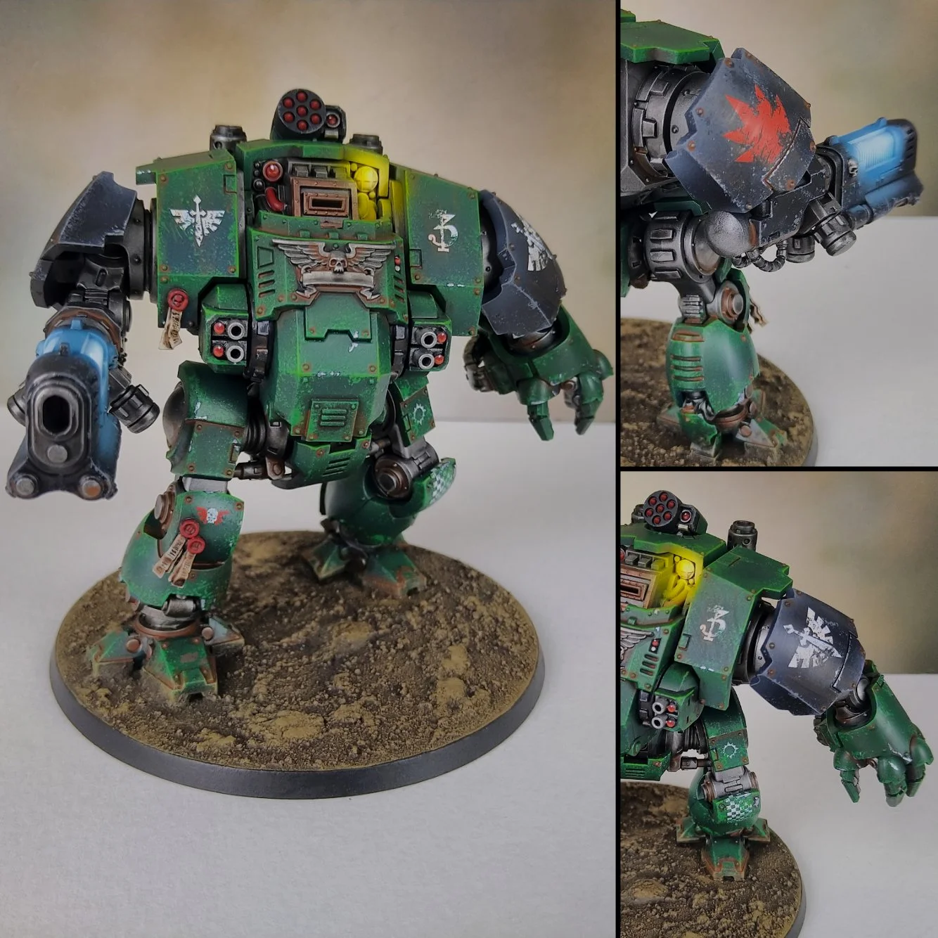 A detailed painted miniature of a green sci-fi mech robot with multiple weapons, decals, and weathering effects, mounted on a textured circular base.