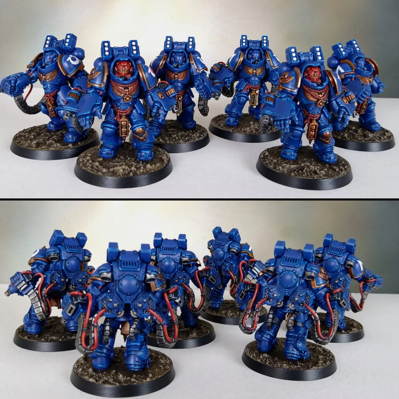 Group of blue-painted Warhammer 40k miniatures with armor and weapons, displayed on round bases.