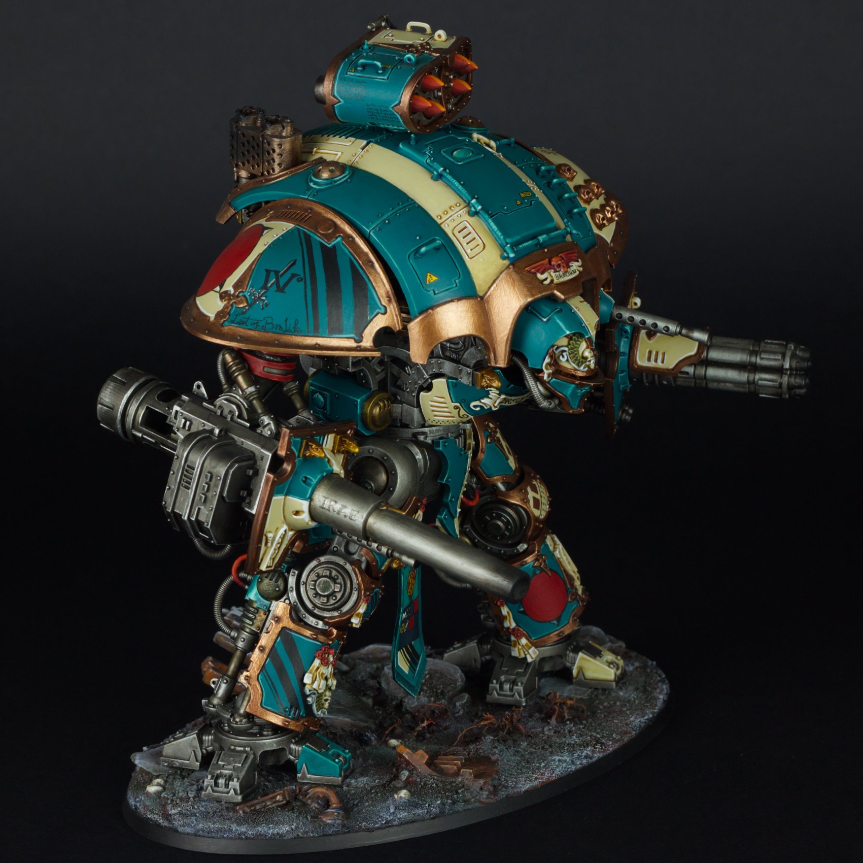 A detailed miniature of a futuristic armored robot with teal, gold, and red accents, standing on a textured base.