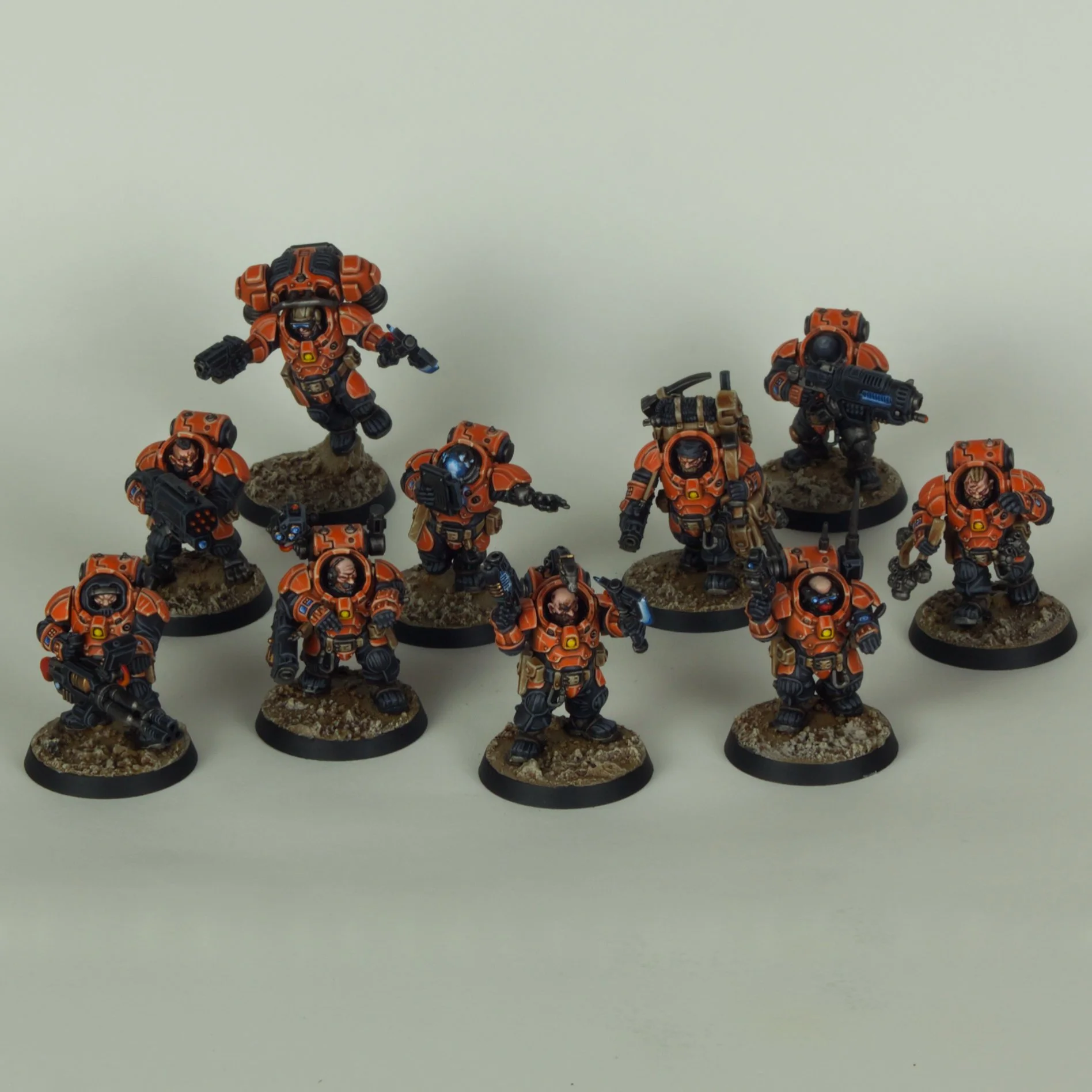 A collection of miniature figurines depicting sci-fi soldiers in orange armor, standing on textured bases against a plain white background.
