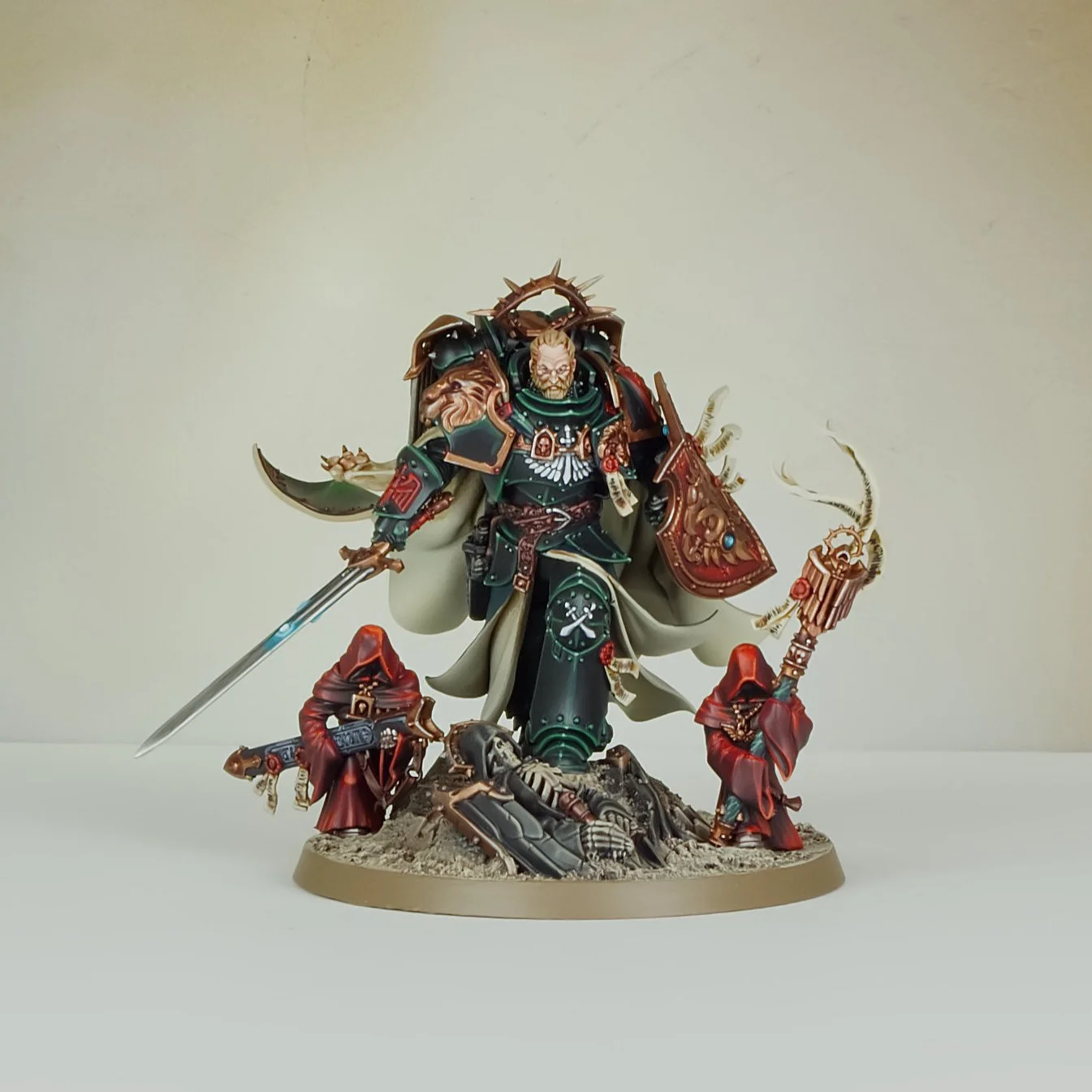 A detailed miniature figurine of a warrior in green and gold armor, holding a sword and shield, accompanied by smaller armored figures in red cloaks, standing on a textured base.