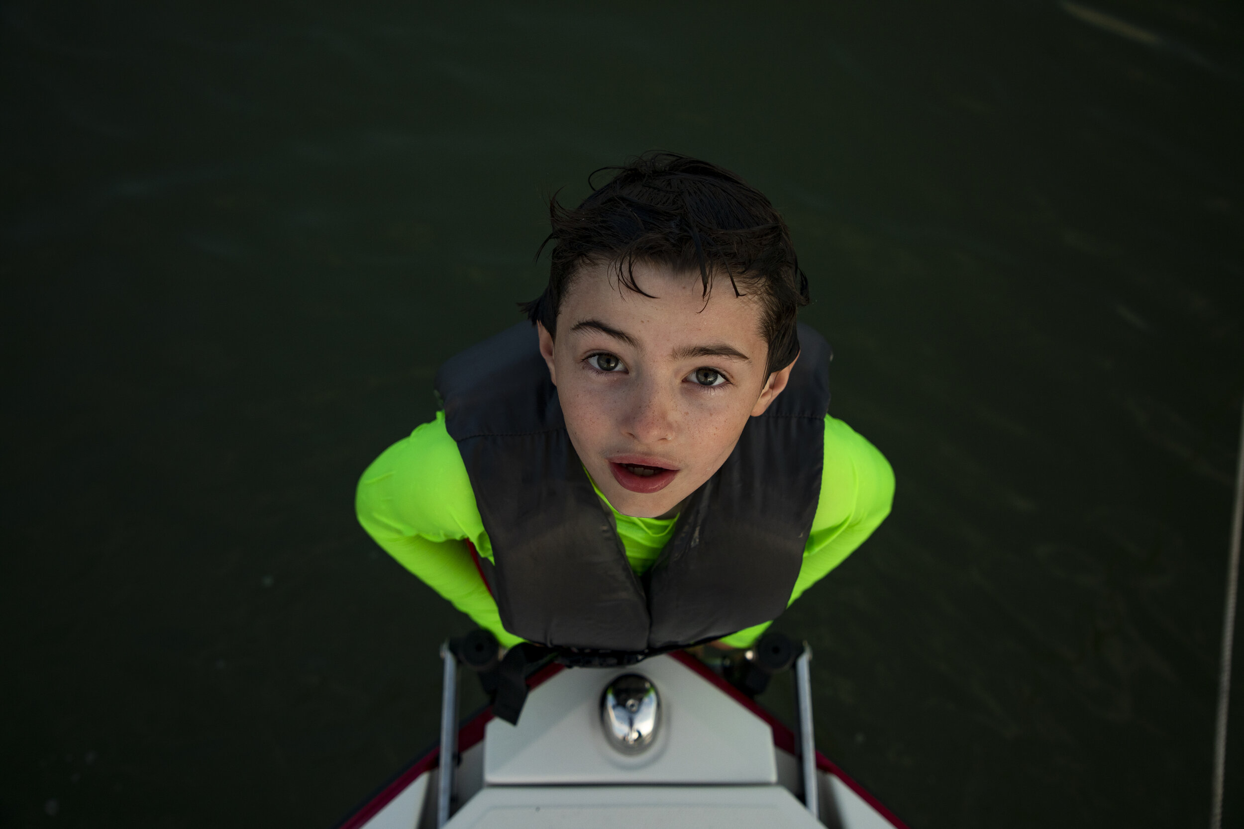 portrait of a young boy swimming off of a boat. Upstate New York Photographer.