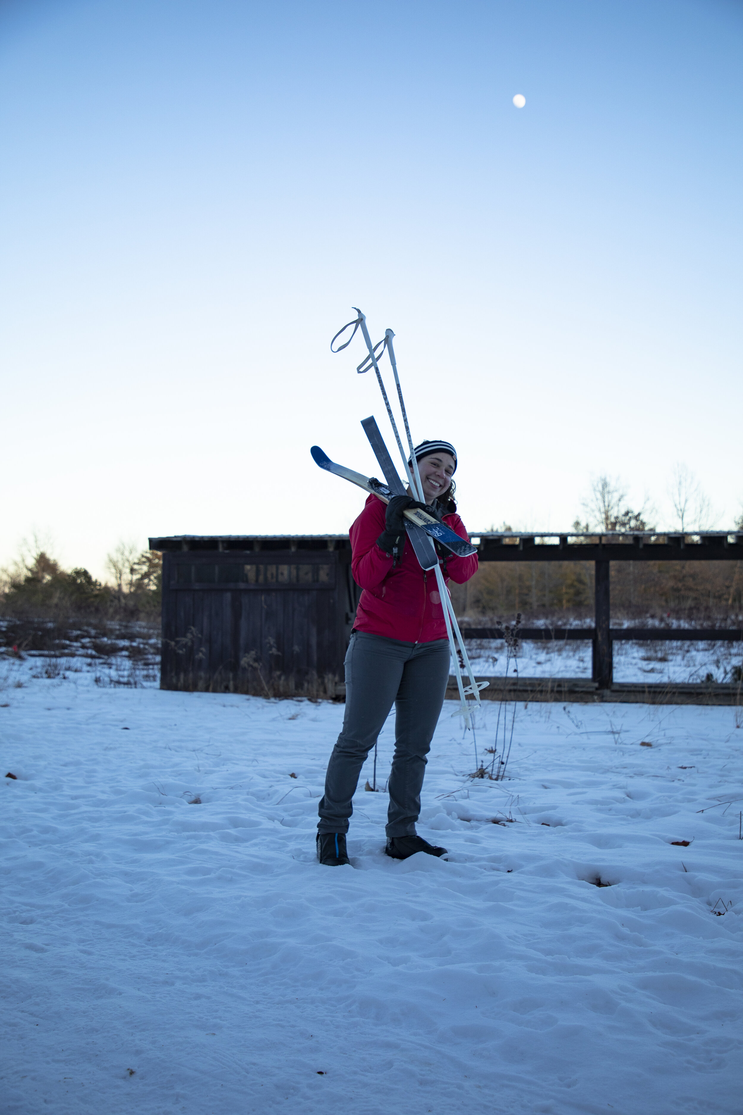 Portrait of a woman carrying her XC ski's during blue hour. Upstate New York Photographer.