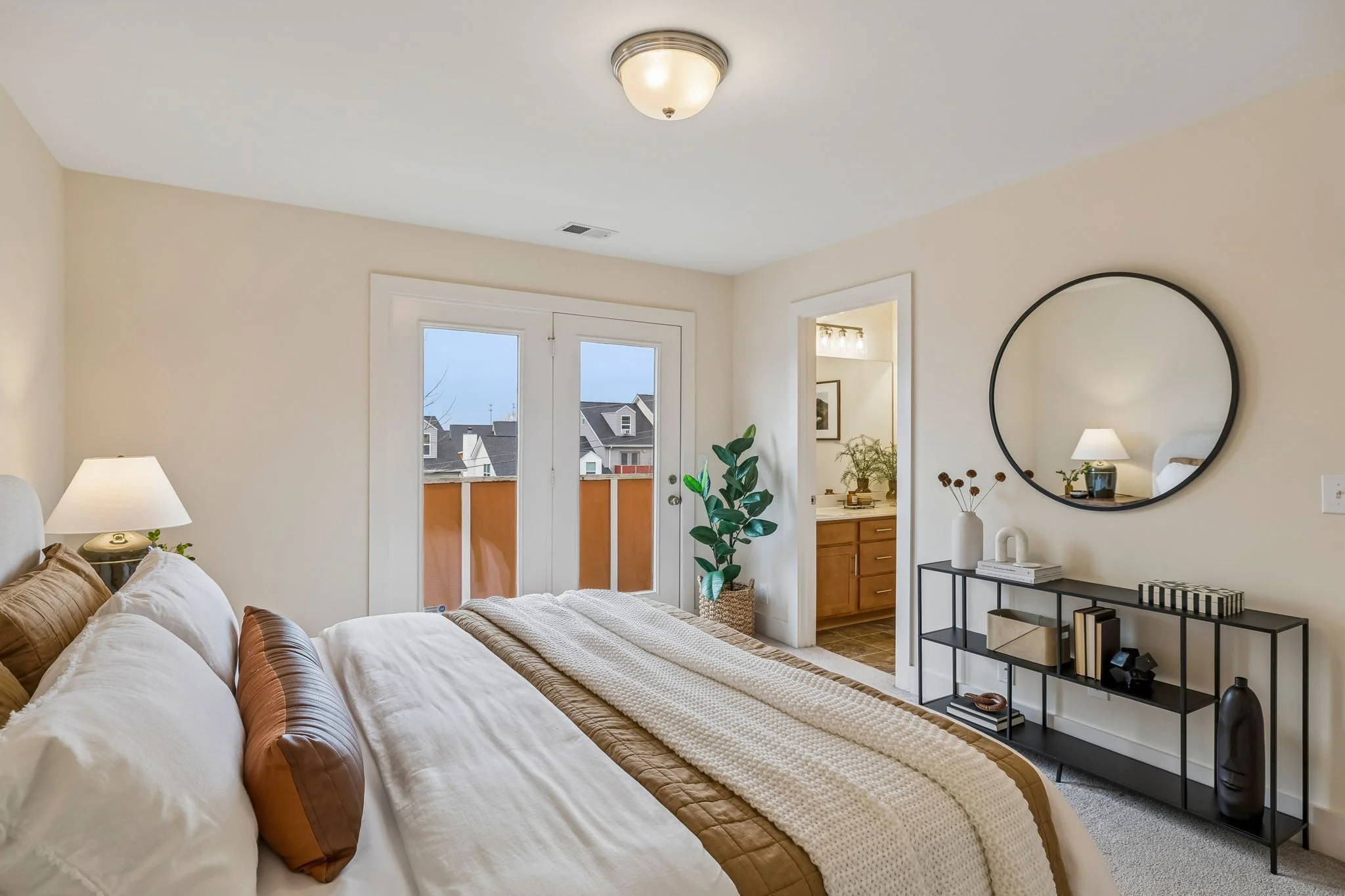 Bedroom Image Showing Console with Round Mirror Above and Plant in Corner