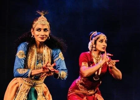 two femail dancers one in red and one in blue holding poses