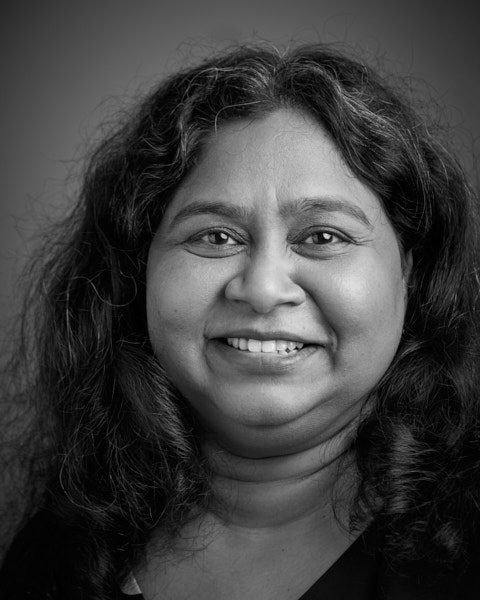 Black and white close-up portrait of a smiling woman with curly hair.