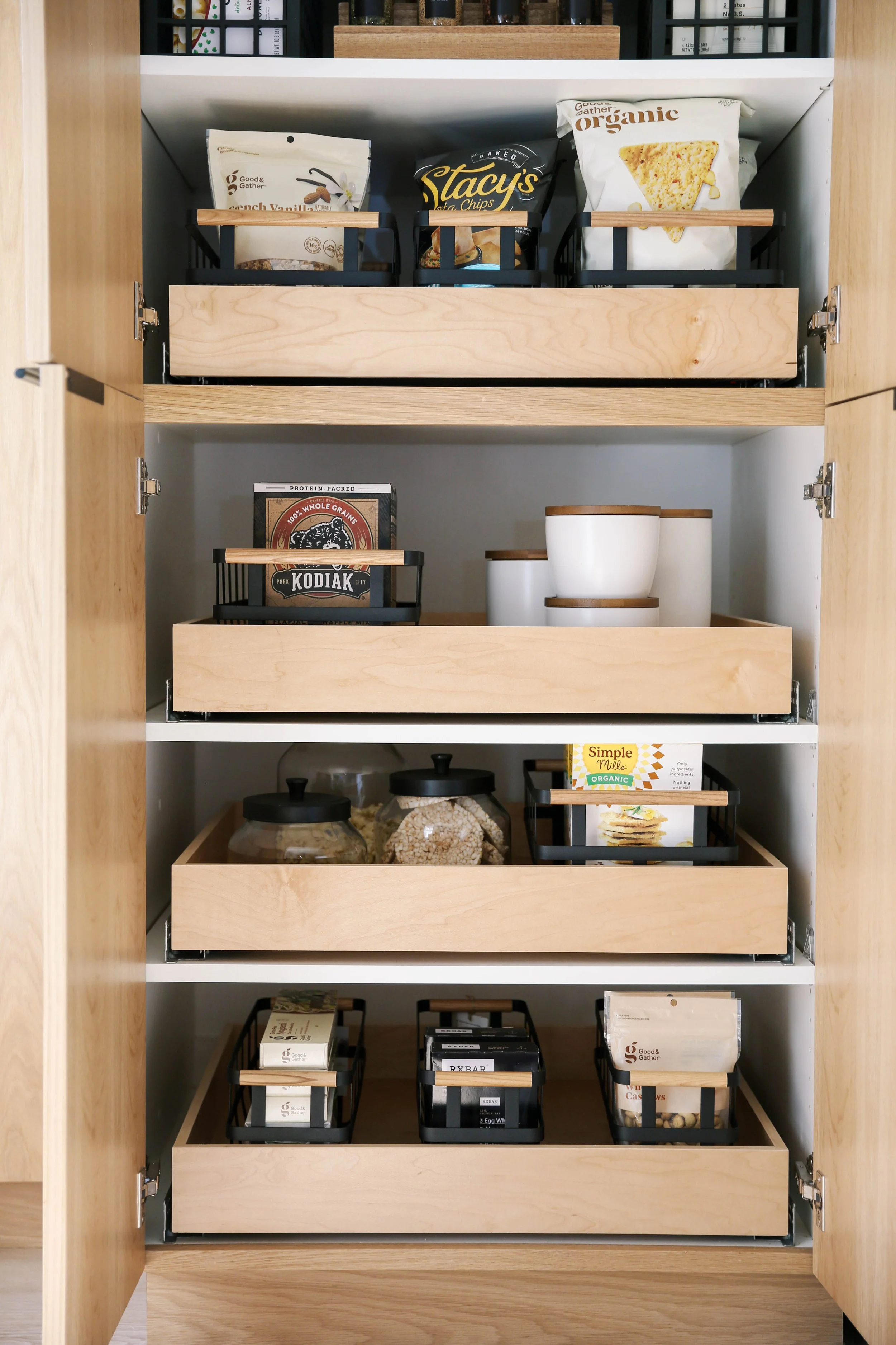 Tall kitchen pantry organized with snacks, breakfast foods, canisters and pull-out storage drawers.