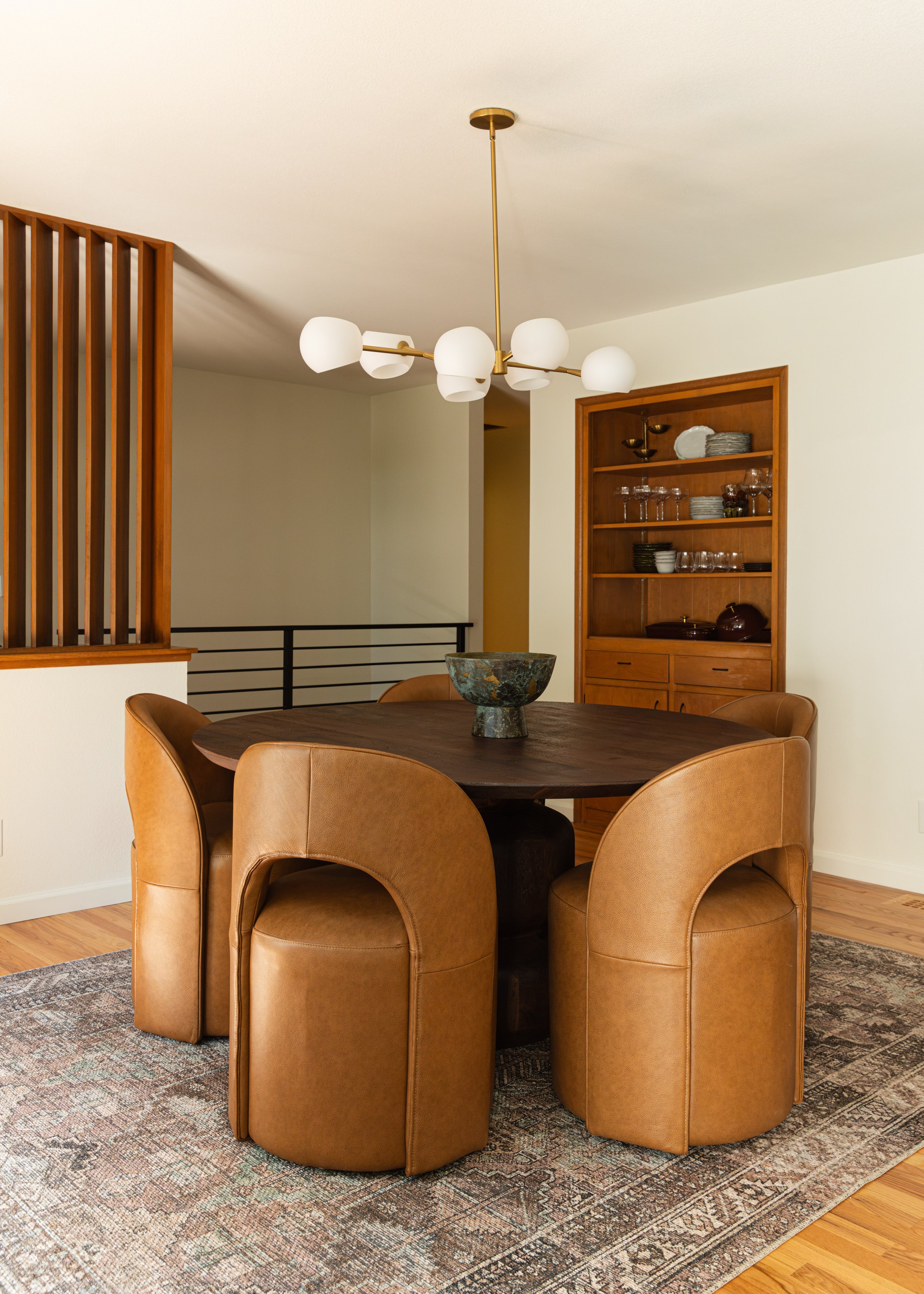 Mid-century modern dining room with statement chandelier, original built-in hutch, and custom partition wall in a Portland remodel.