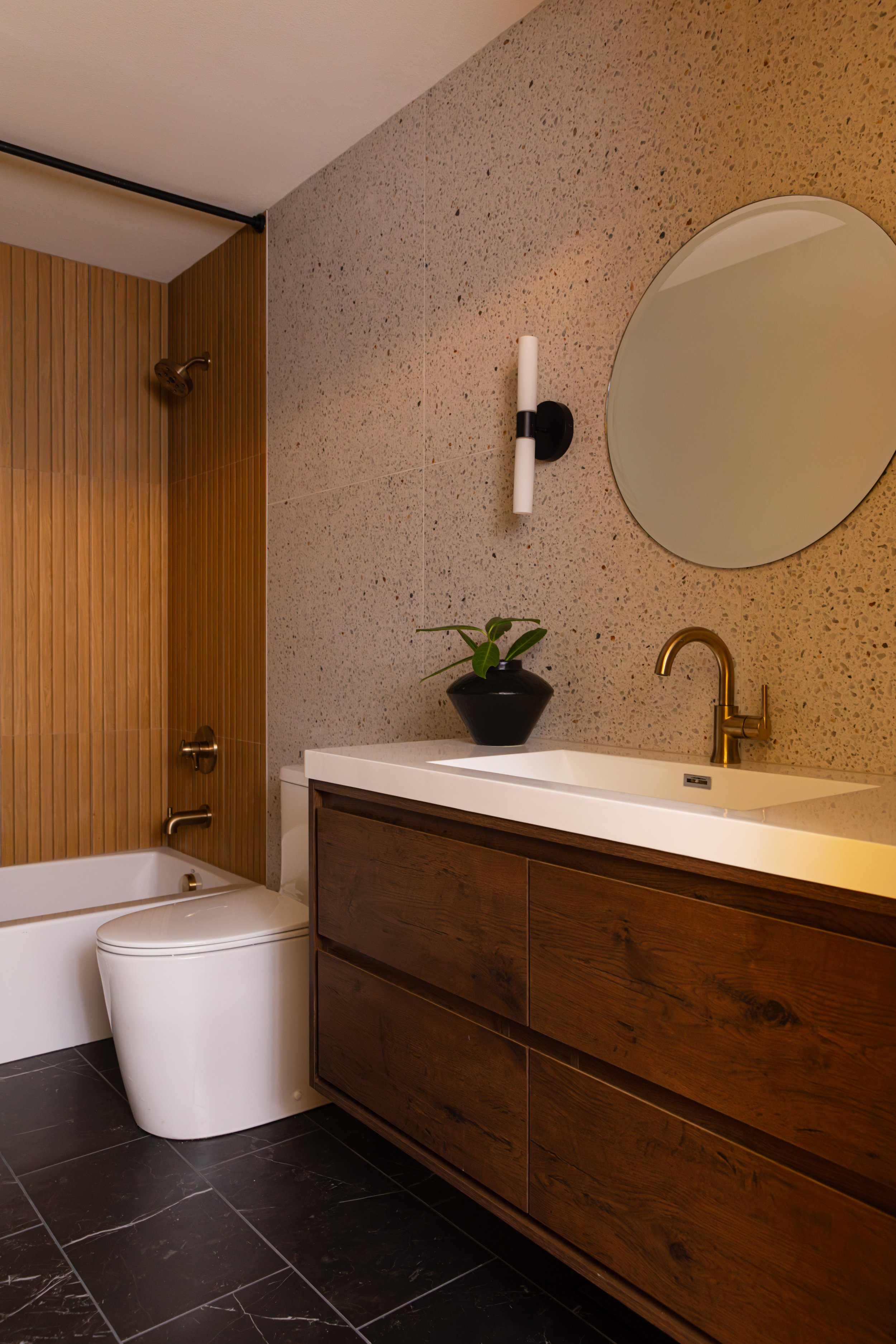 Upstairs hallway bathroom with wood-look fluted tile tub surround, terrazzo wall tile, and custom wood vanity in a Portland remodel.