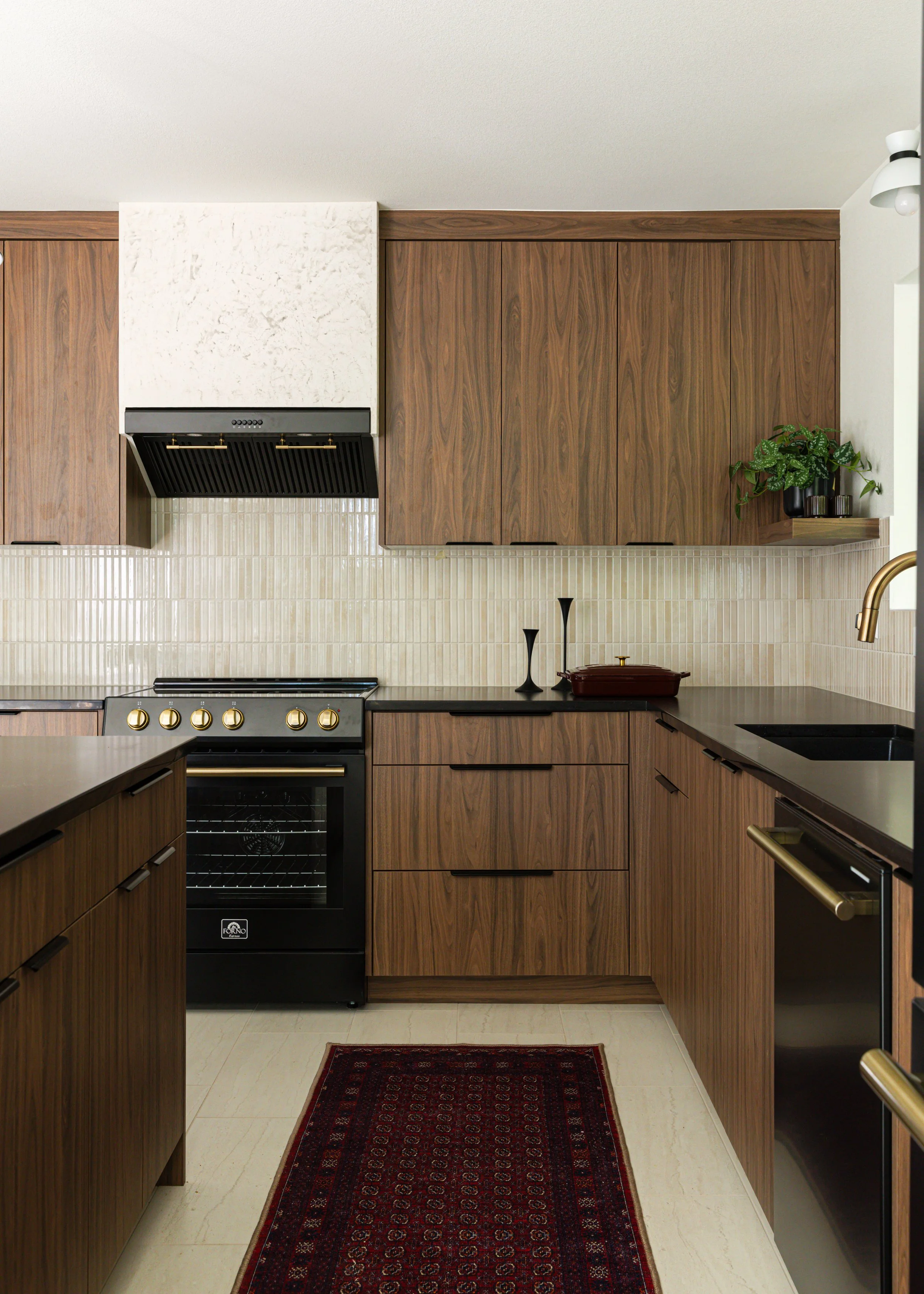 Mid-century modern kitchen remodel with custom walnut cabinetry, black quartz countertops, and brass lighting in a Portland design-build renovation.