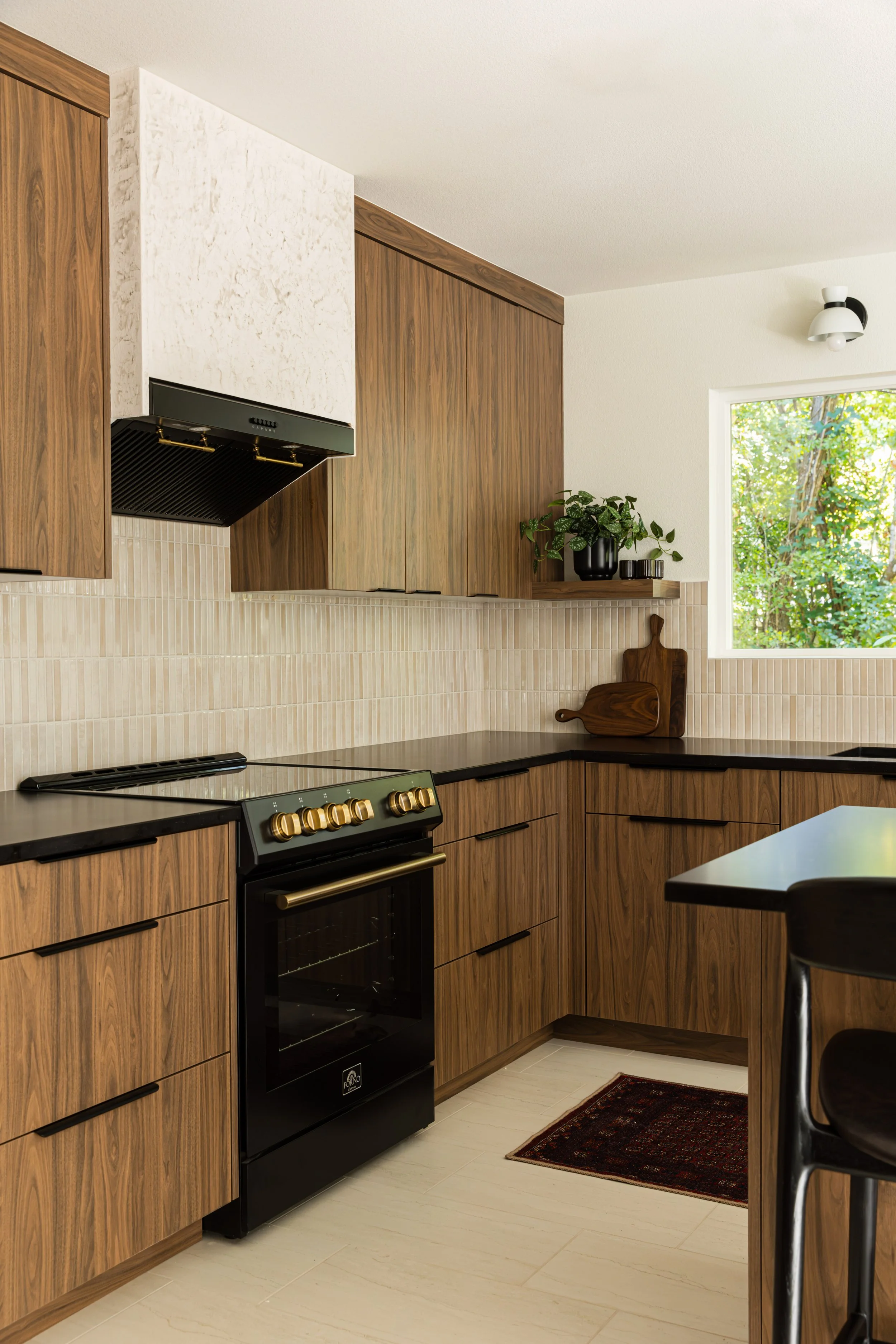 Kitchen range with custom Venetian plaster hood, vertical tile backsplash, and walnut cabinetry in a Portland design-build remodel.