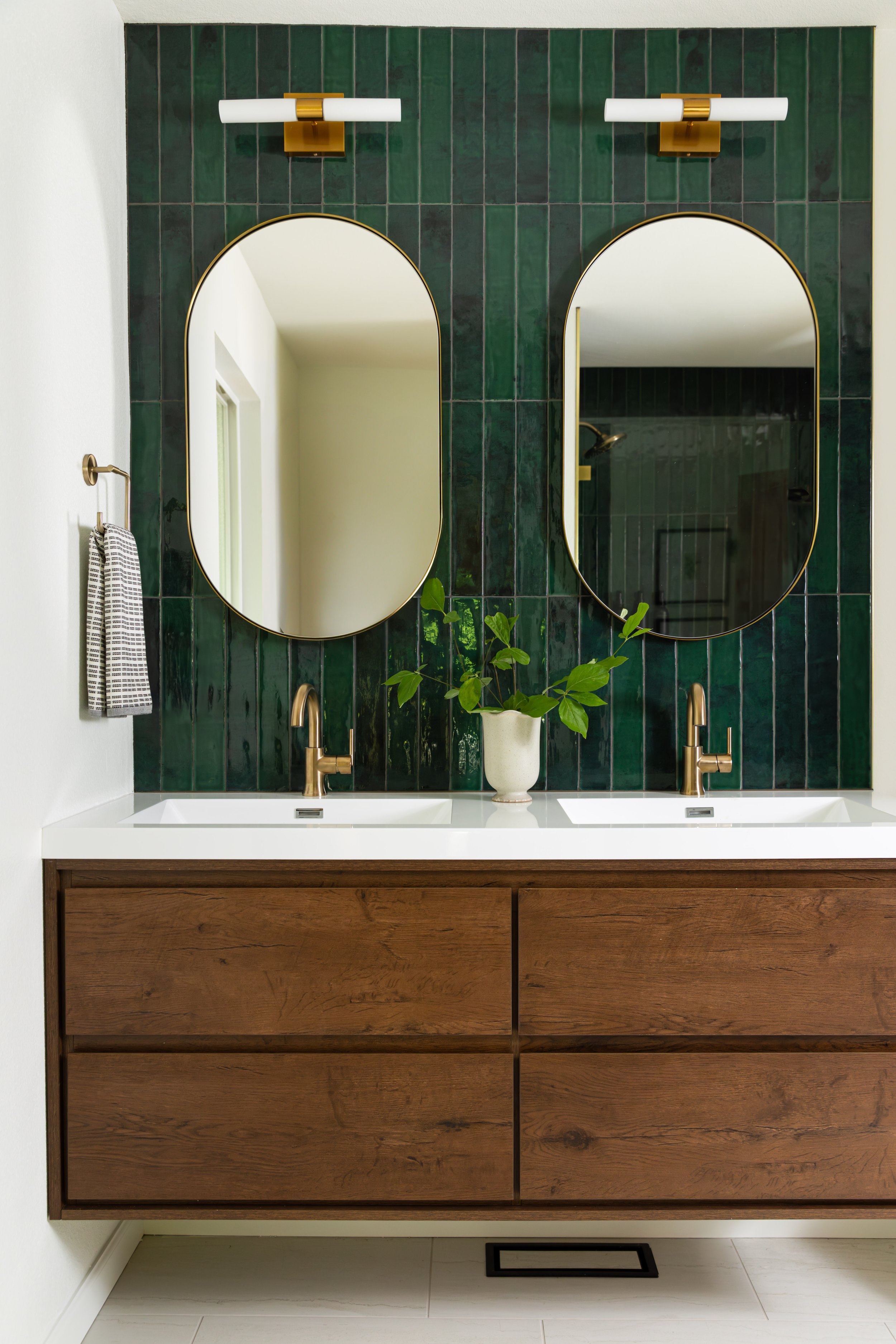 Primary bathroom double vanity with green vertical tile, brass fixtures, and custom wood cabinetry in a Portland mid-century modern remodel.