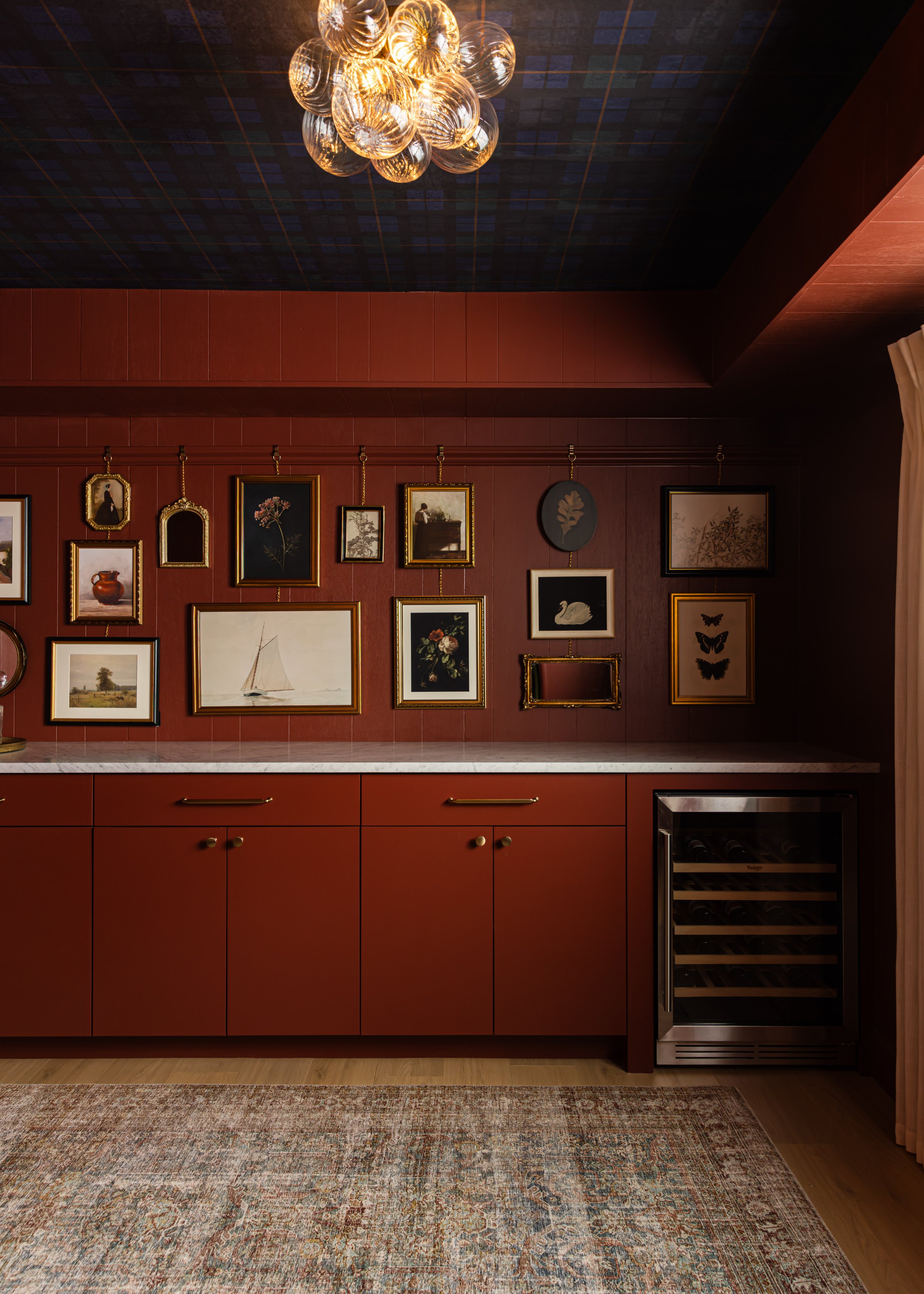 Hidden speakeasy with Sweet Rosy Brown cabinetry, gallery wall, wine refrigerator and brass bubble chandelier.