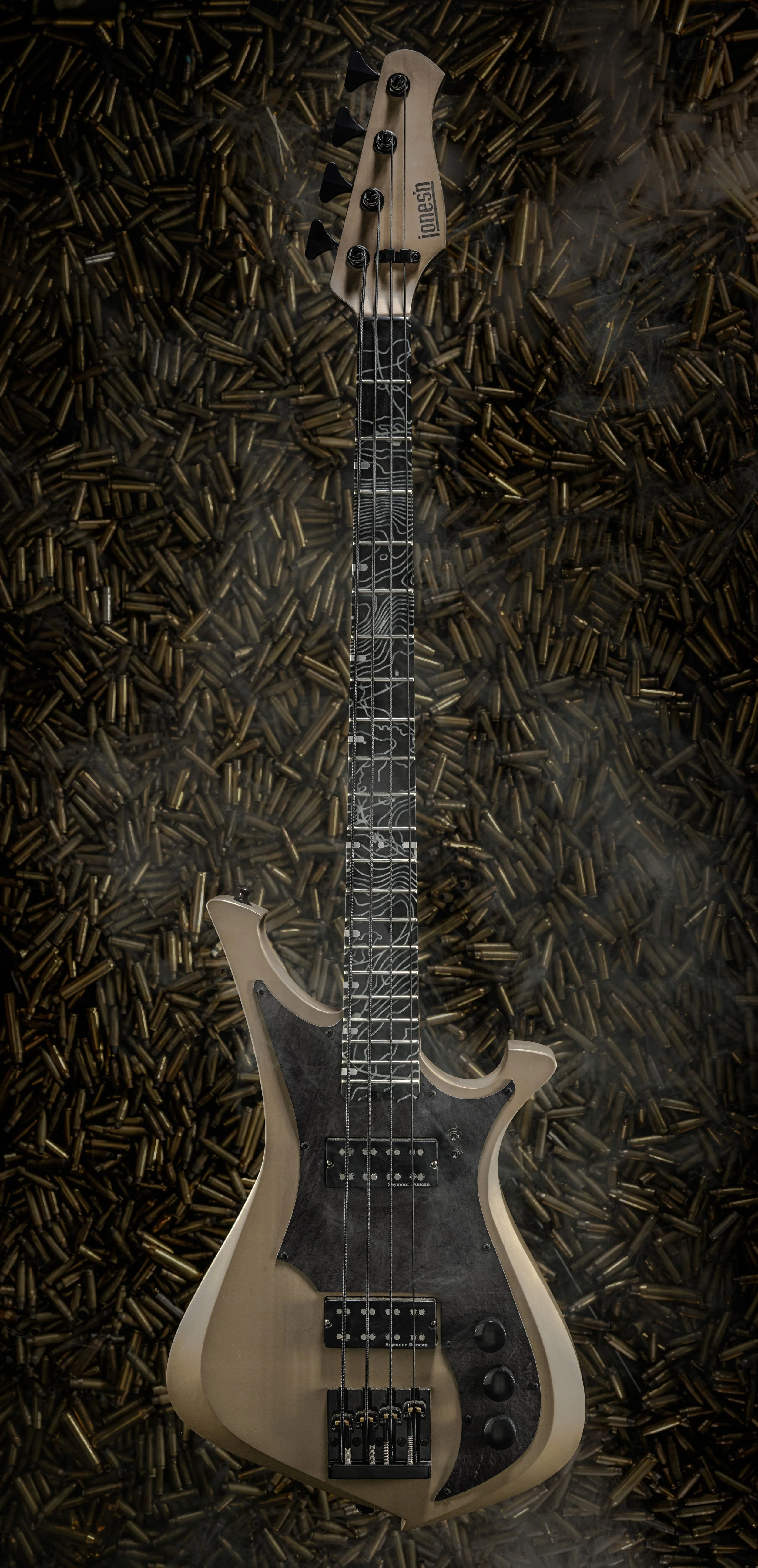 A custom guitar with a topographical fretboard positioned on a pile of spent ammo casings.