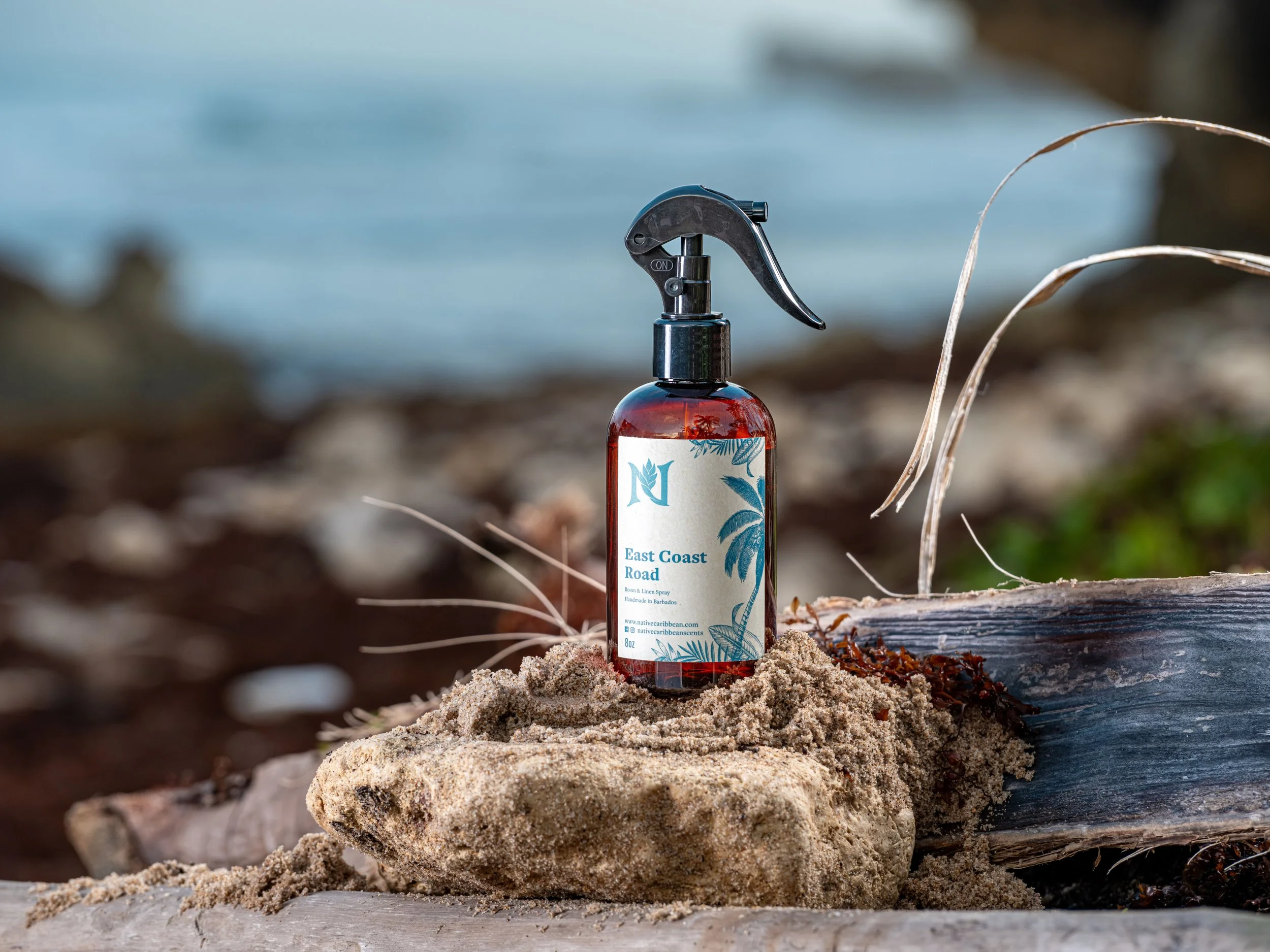 An advertisement for a tropical room spray photographed on a rocky tropical coastline.