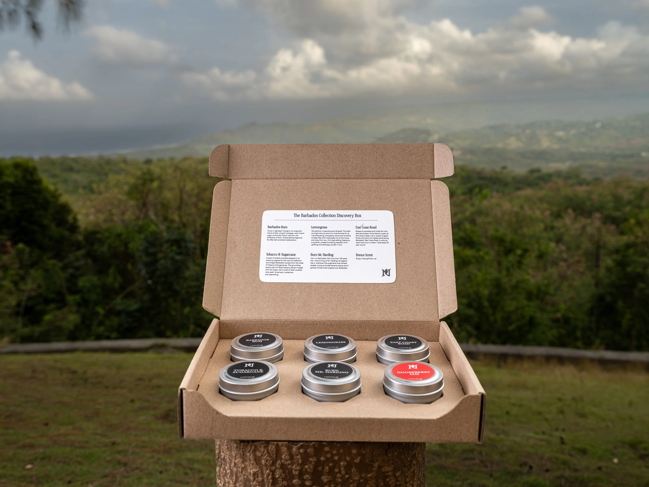  A six candle gift set product photographed on a tropical mountain top with views of forest and ocean in the background.