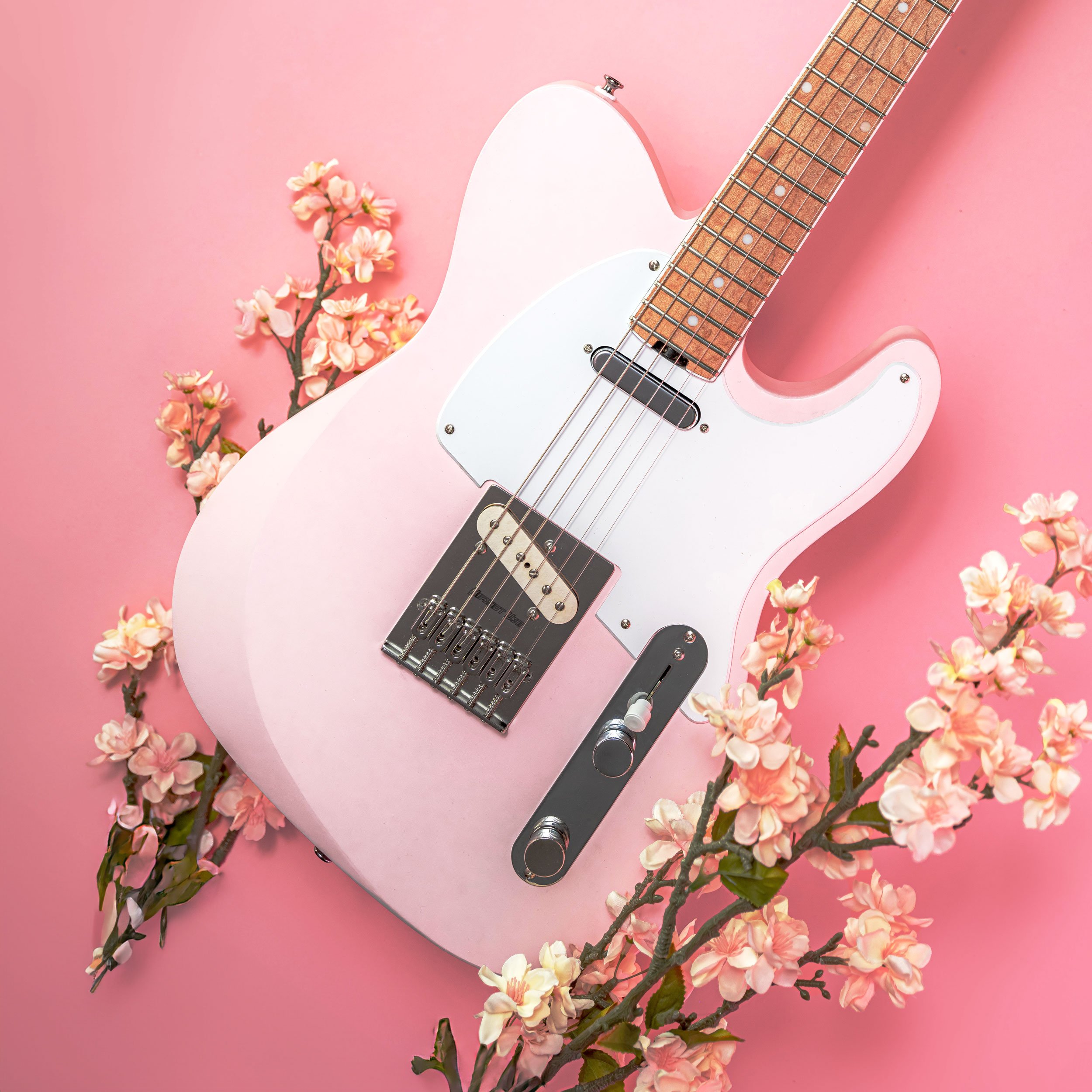 Pink electric guitar surrounded by pink cherry blossoms on a pink background for a seasonal advertisement.