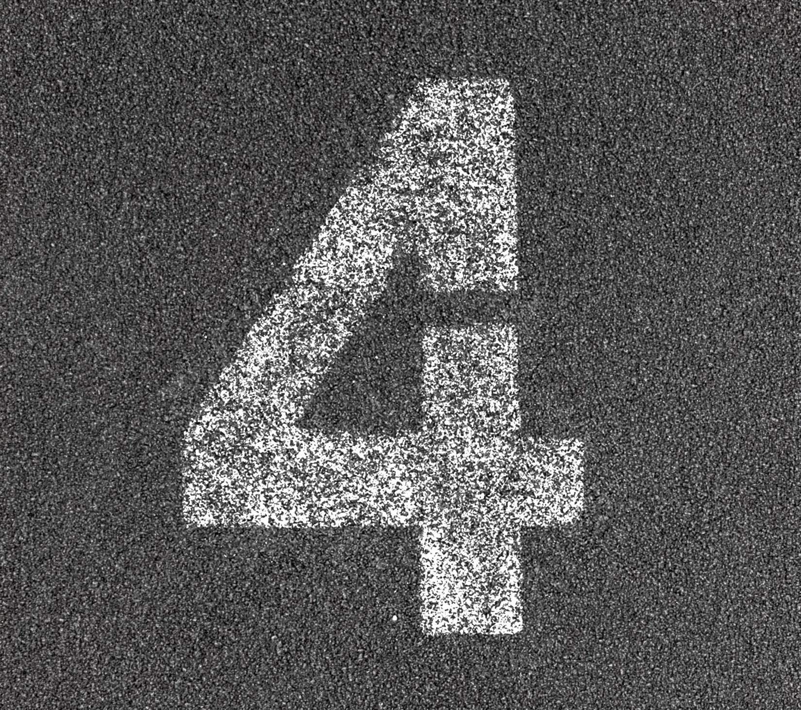 A white painted number 4 on a dark rubber surface