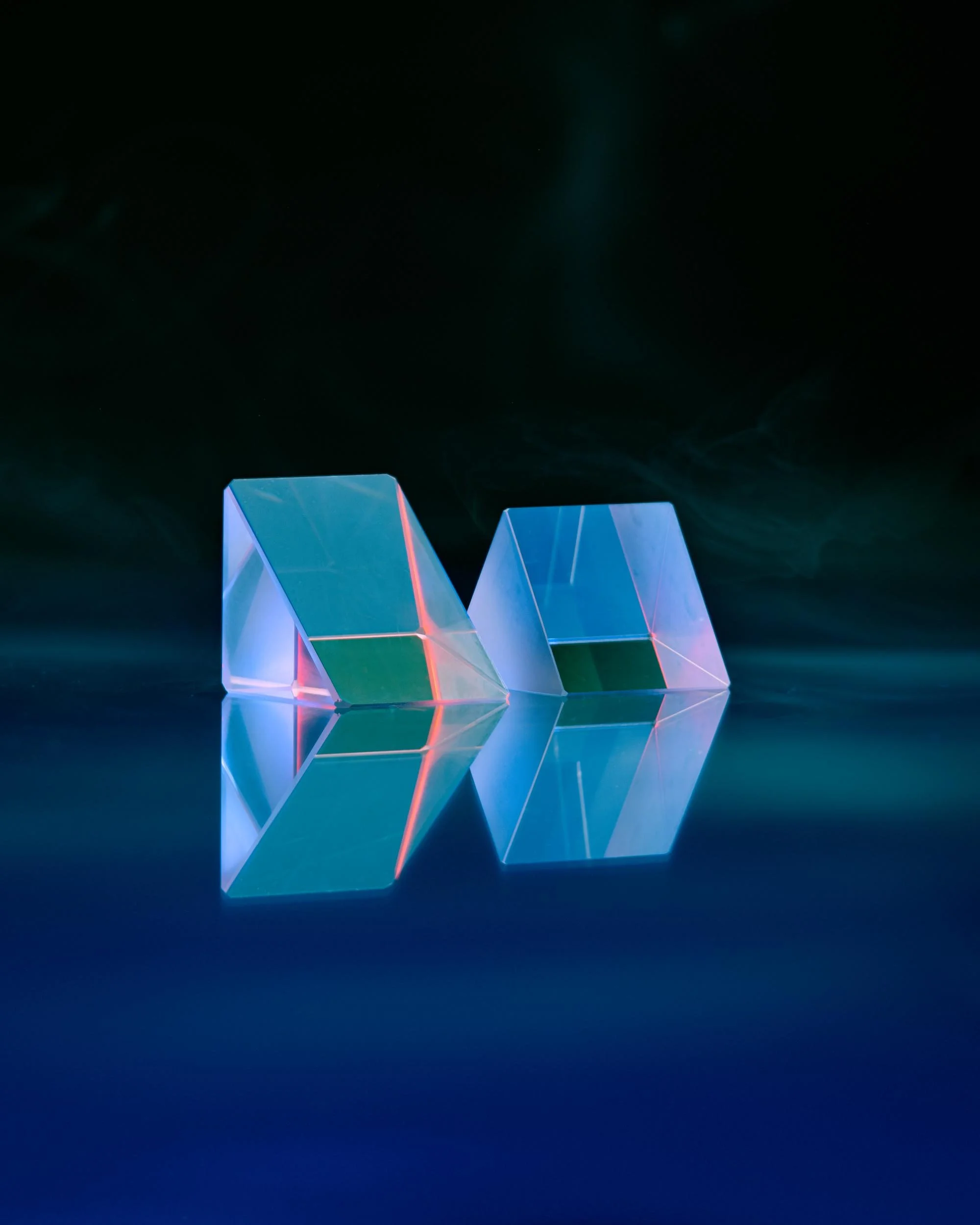 A precision product photograph of two perfect prisms on a creative lighting set.