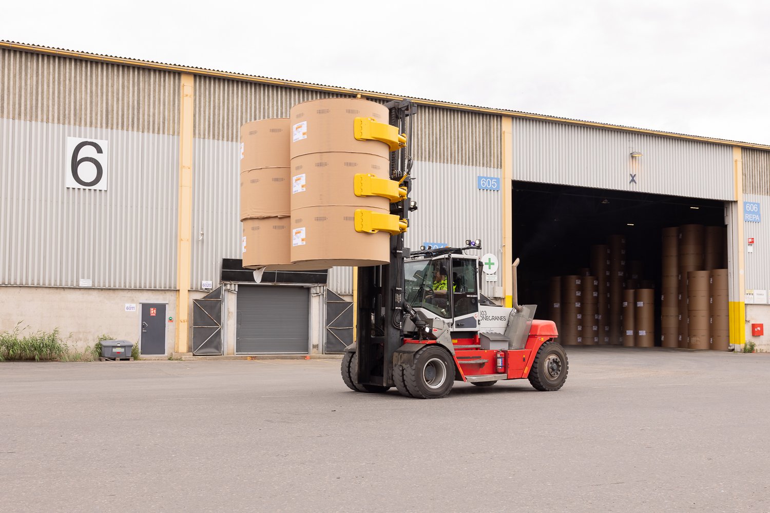 forklifts, equipped with paper roll clamps, precisely handle and transport large cardboard reels