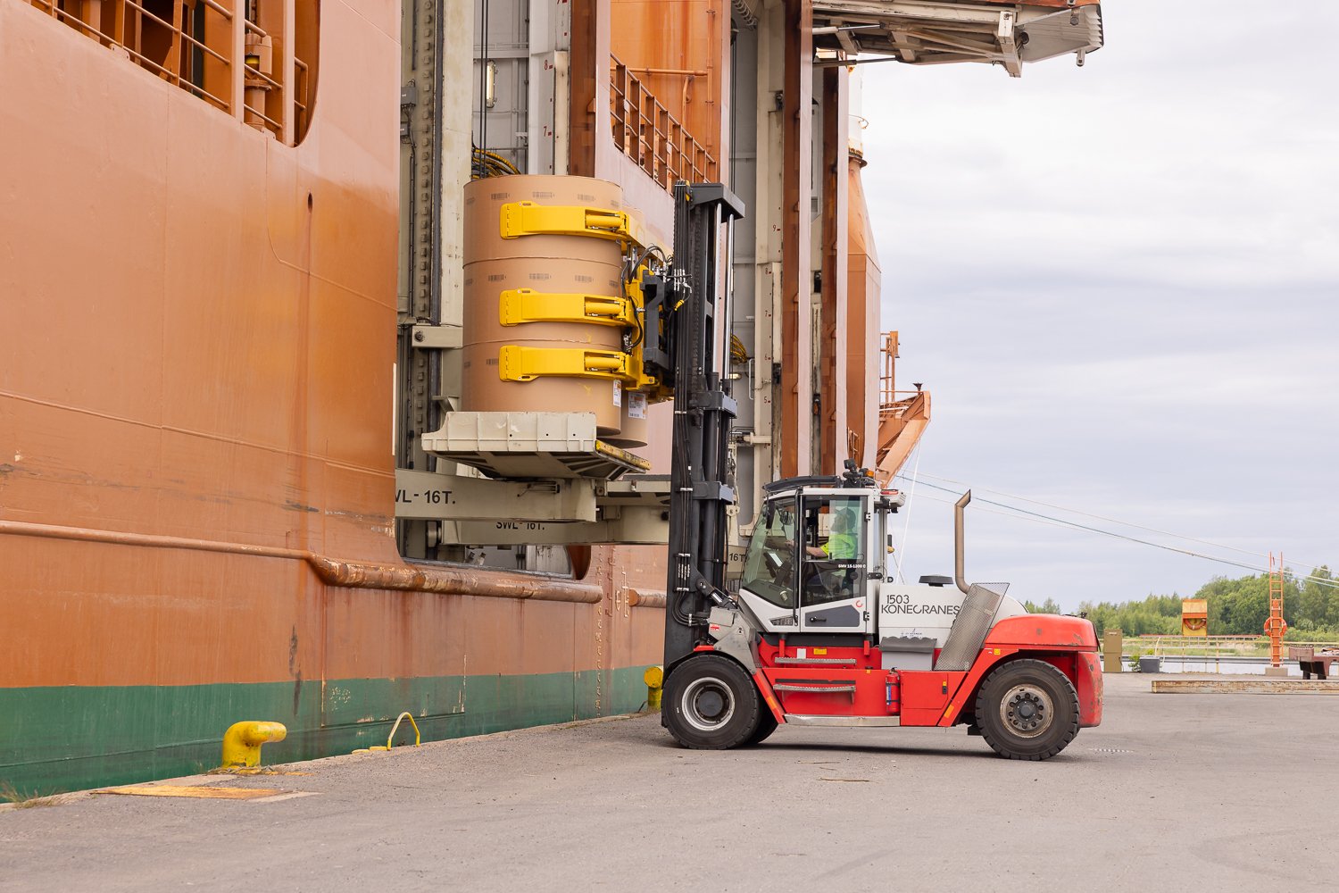 forklifts, equipped with paper roll clamps, precisely handle and transport large cardboard reels to ship