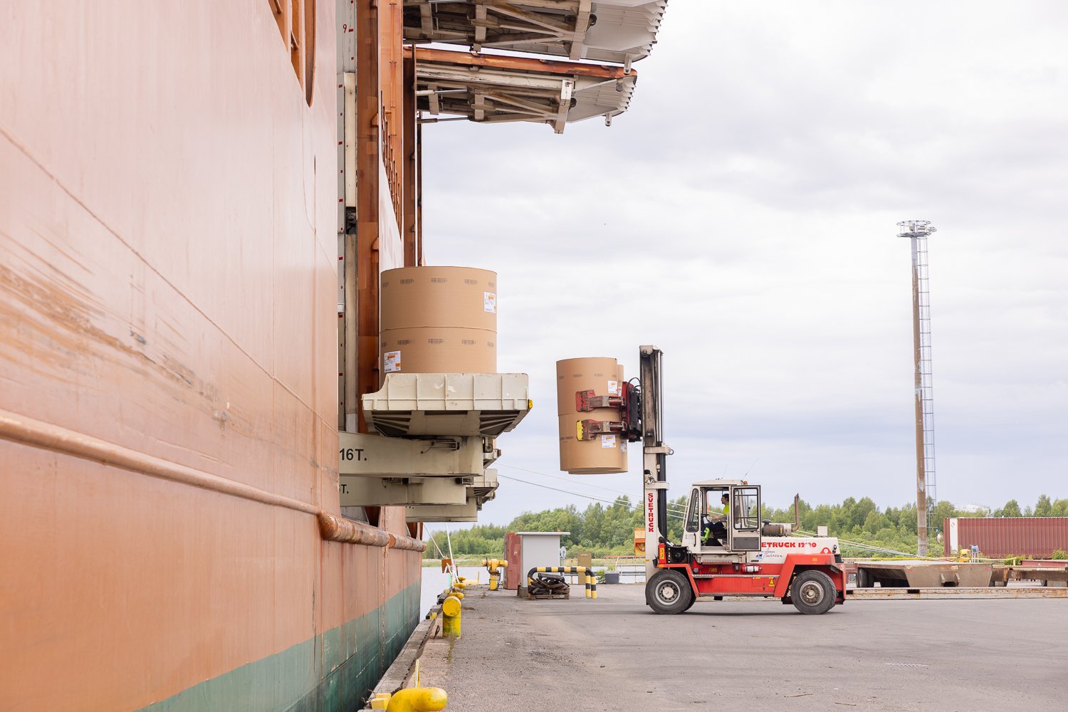 forklifts, equipped with paper roll clamps, precisely handle and transport large cardboard reels to ship
