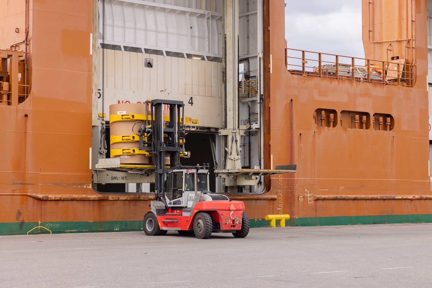 forklifts, equipped with paper roll clamps, precisely handle and transport large cardboard reels to ship