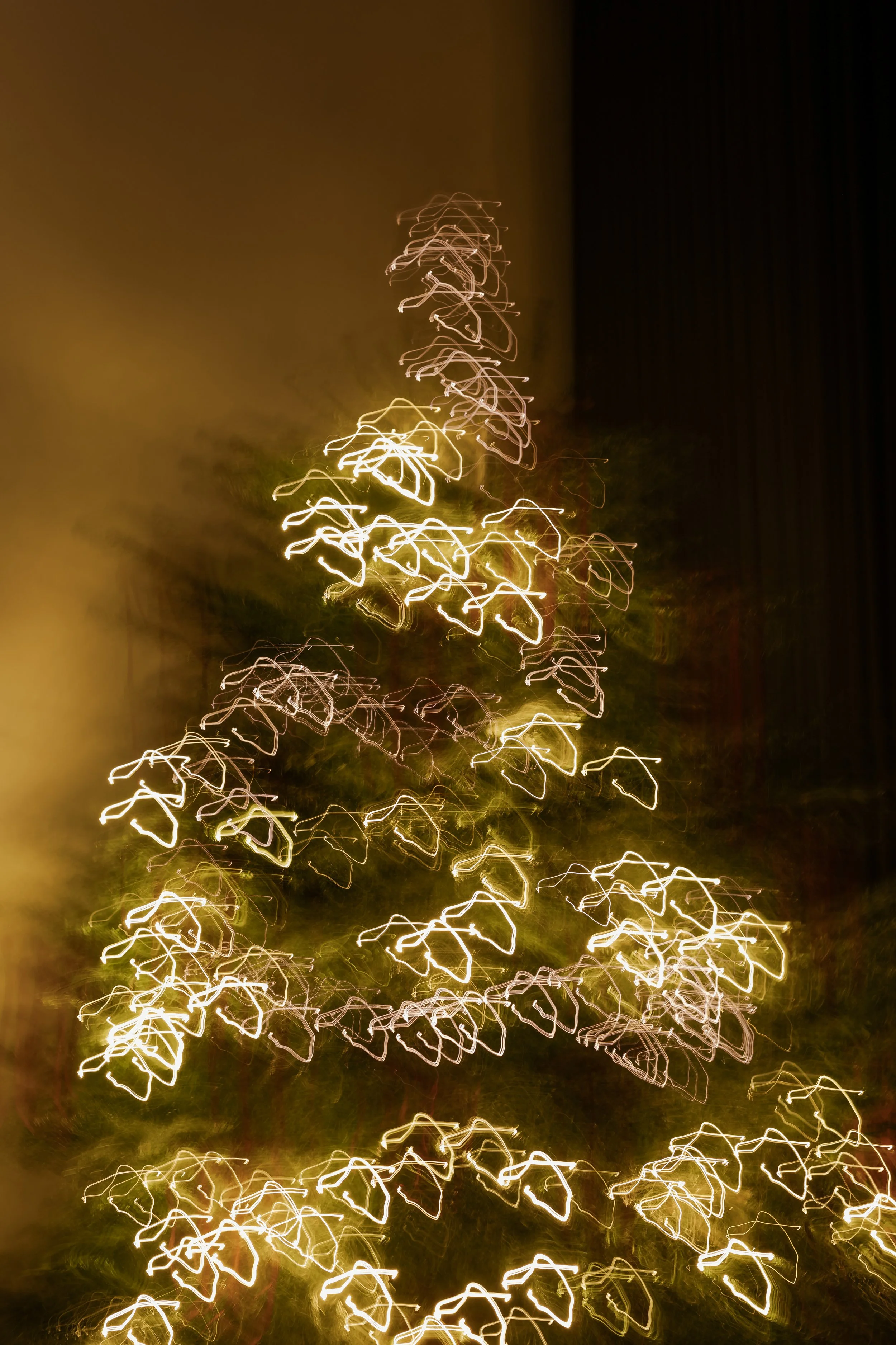 Abstract image of Christmas tree lights creating a pattern of zigzagging lines against a dark background.