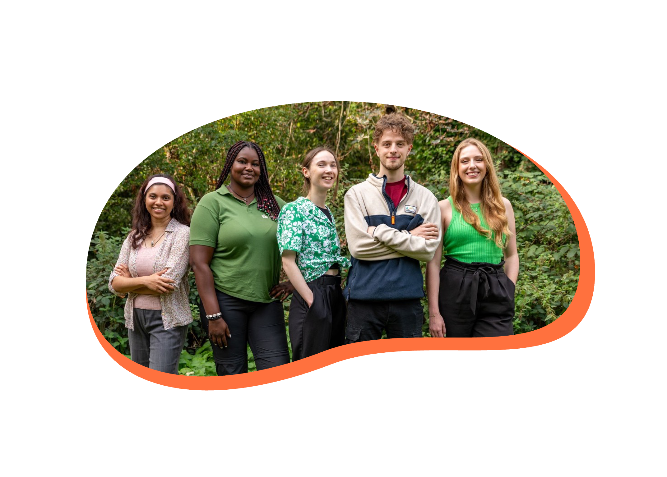 A diverse group of five young people standing outdoors in a natural, wooded setting, smiling at the camera.