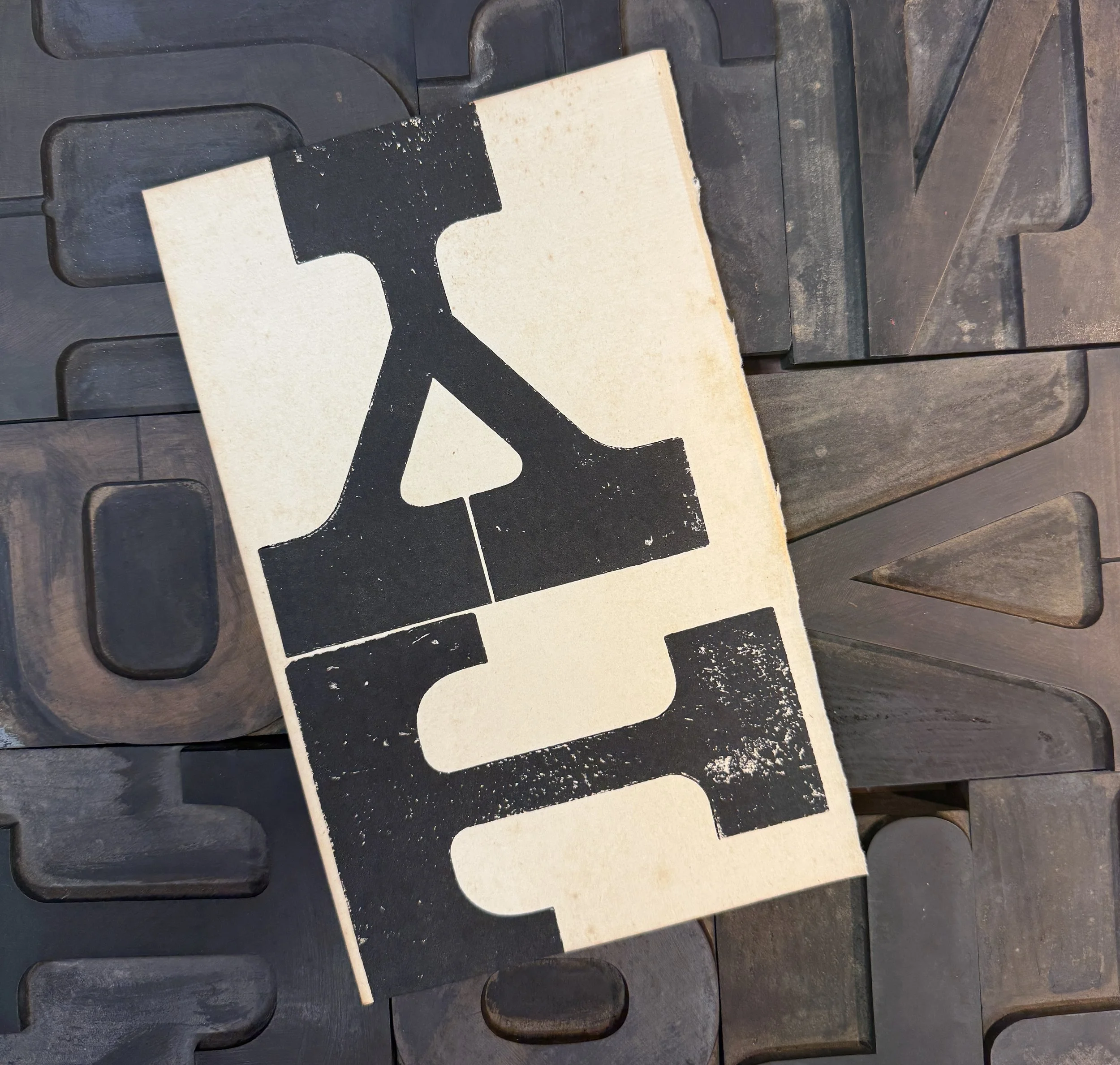 A wooden sign with the word "SALE" in large black distressed letters, resting on a surface made of interlocking wooden tiles.