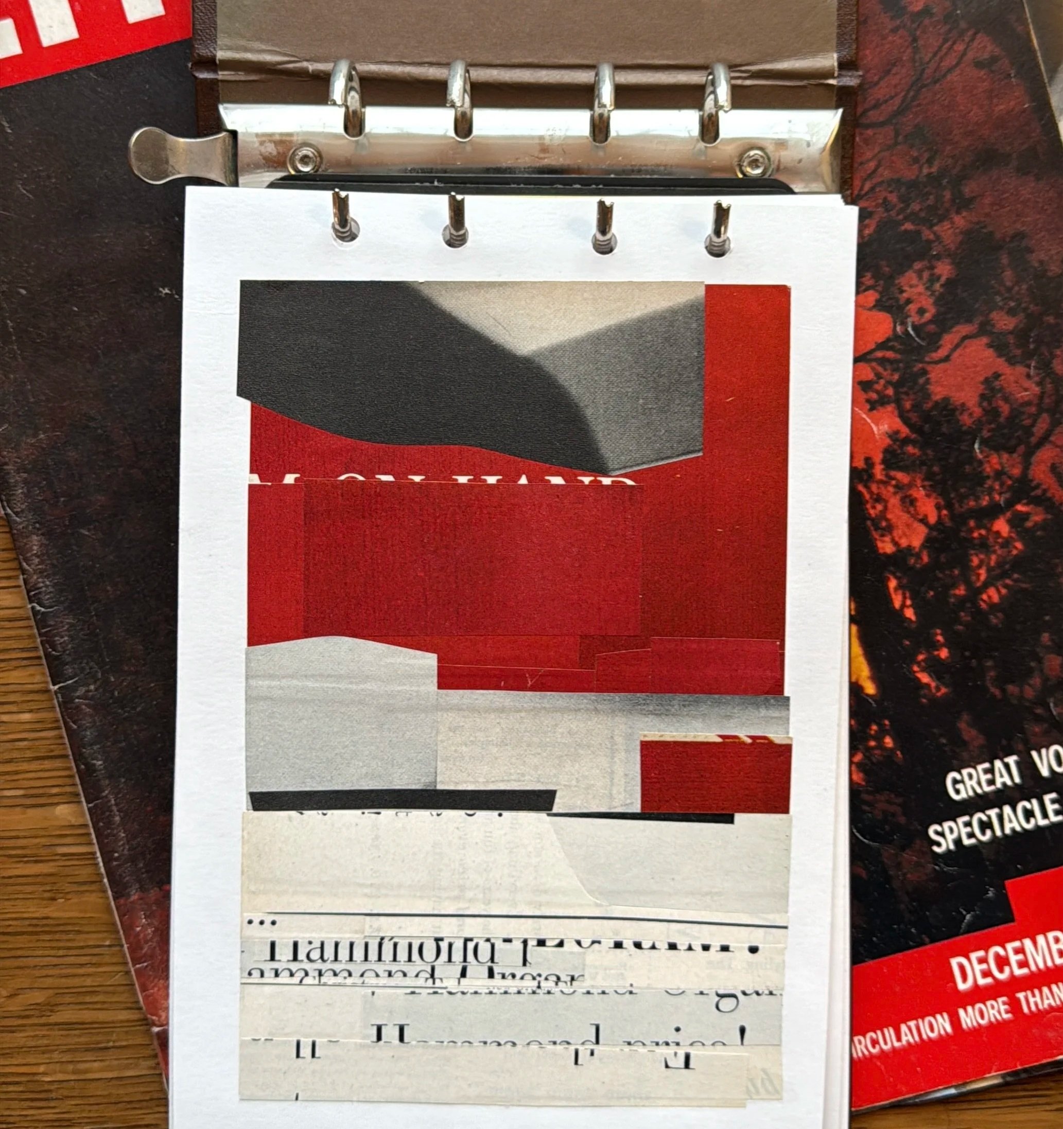 A torn paper flip chart on a wooden surface, with parts of an advertisement or poster that includes black, red, beige, and white colors visible.