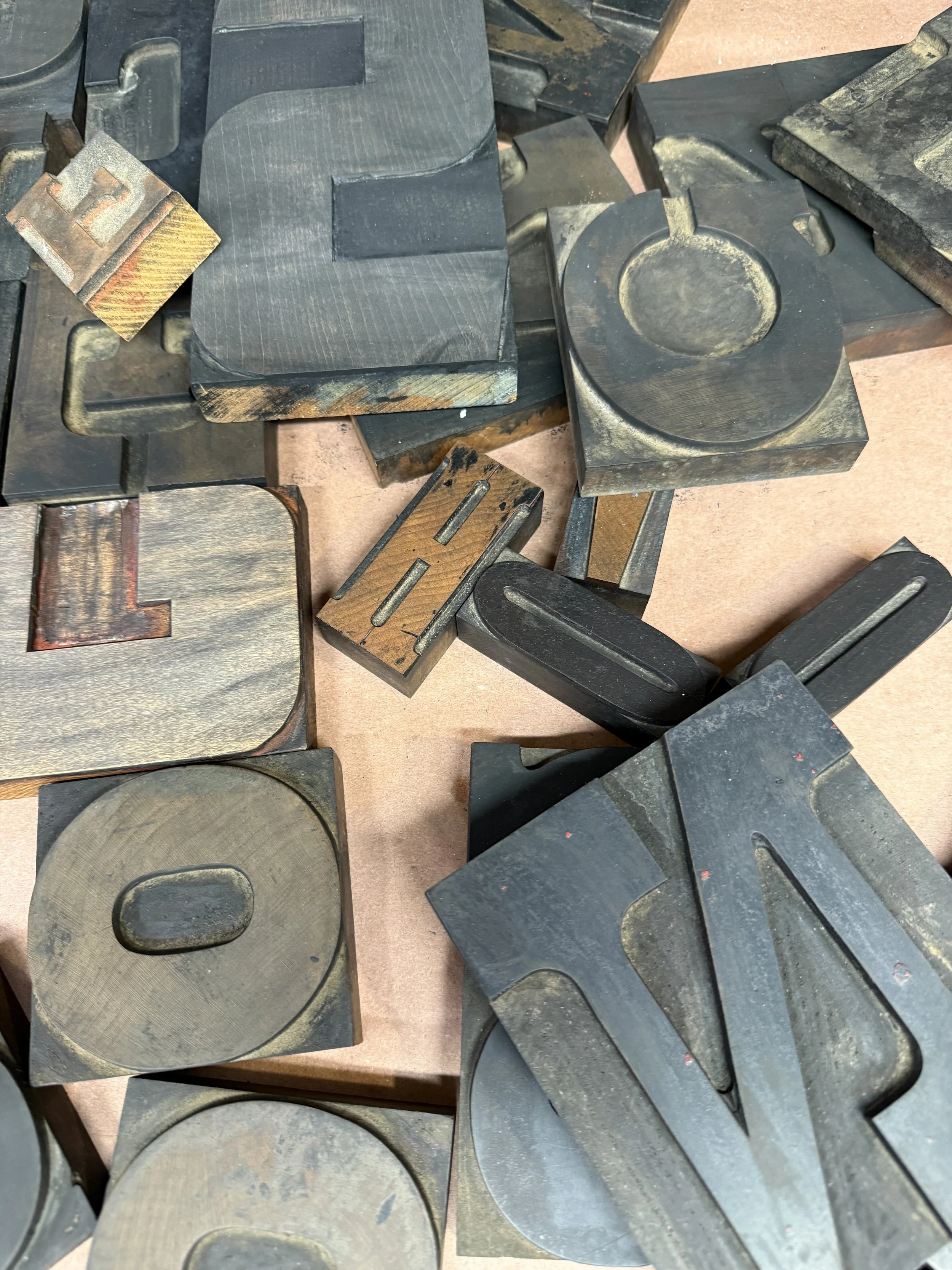 A collection of black metal molds with various shapes, including circles, rectangles, and complex geometric forms, arranged on a wooden surface.