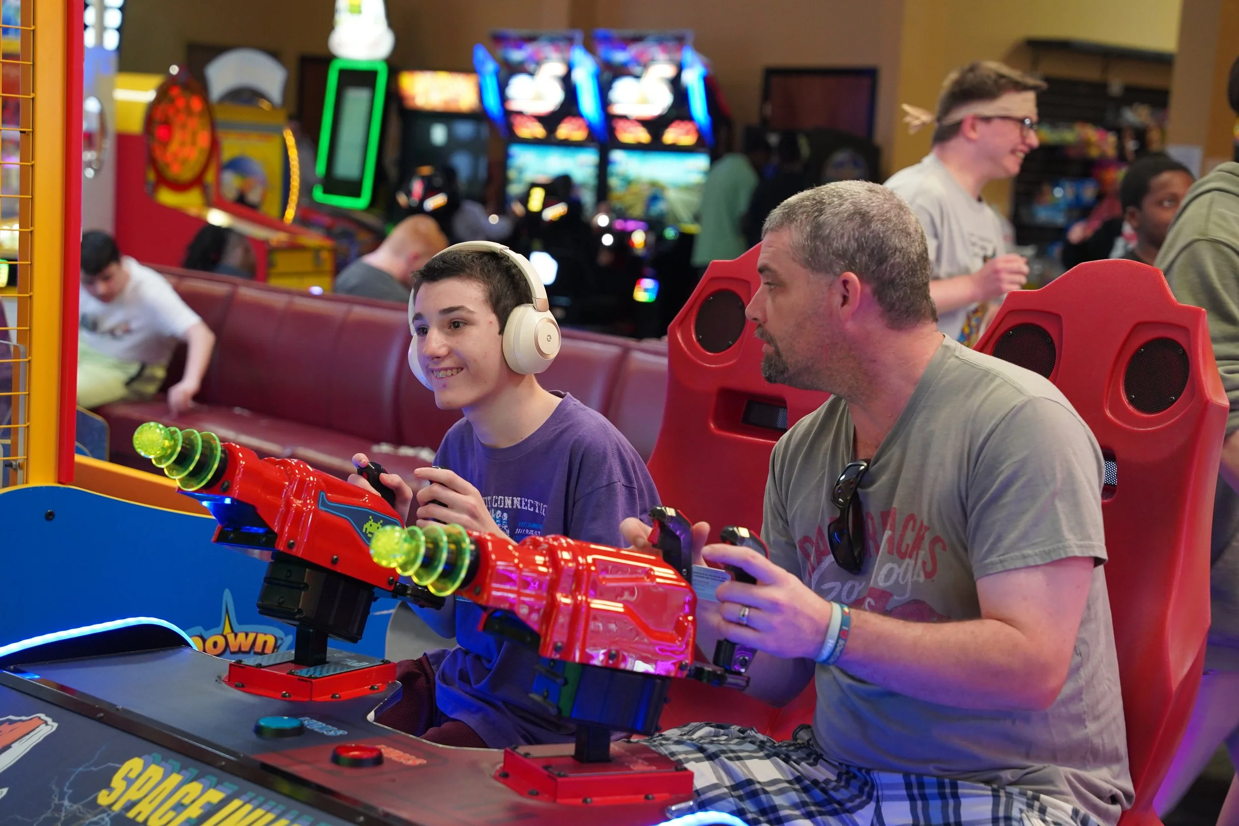teenage boy and volunteer playing spaceship arcade game