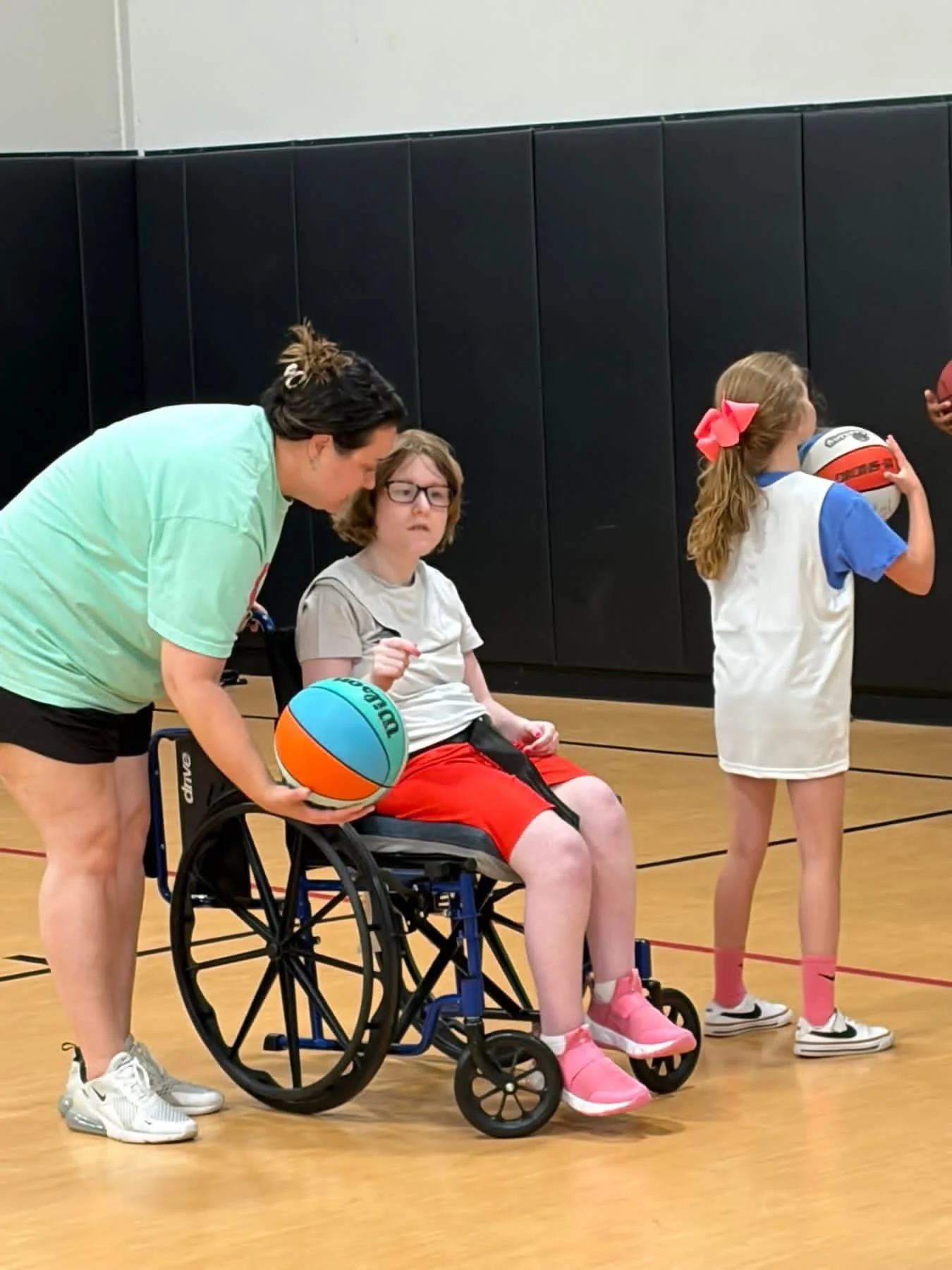 volunteer helping a child in wheelchair play basketball