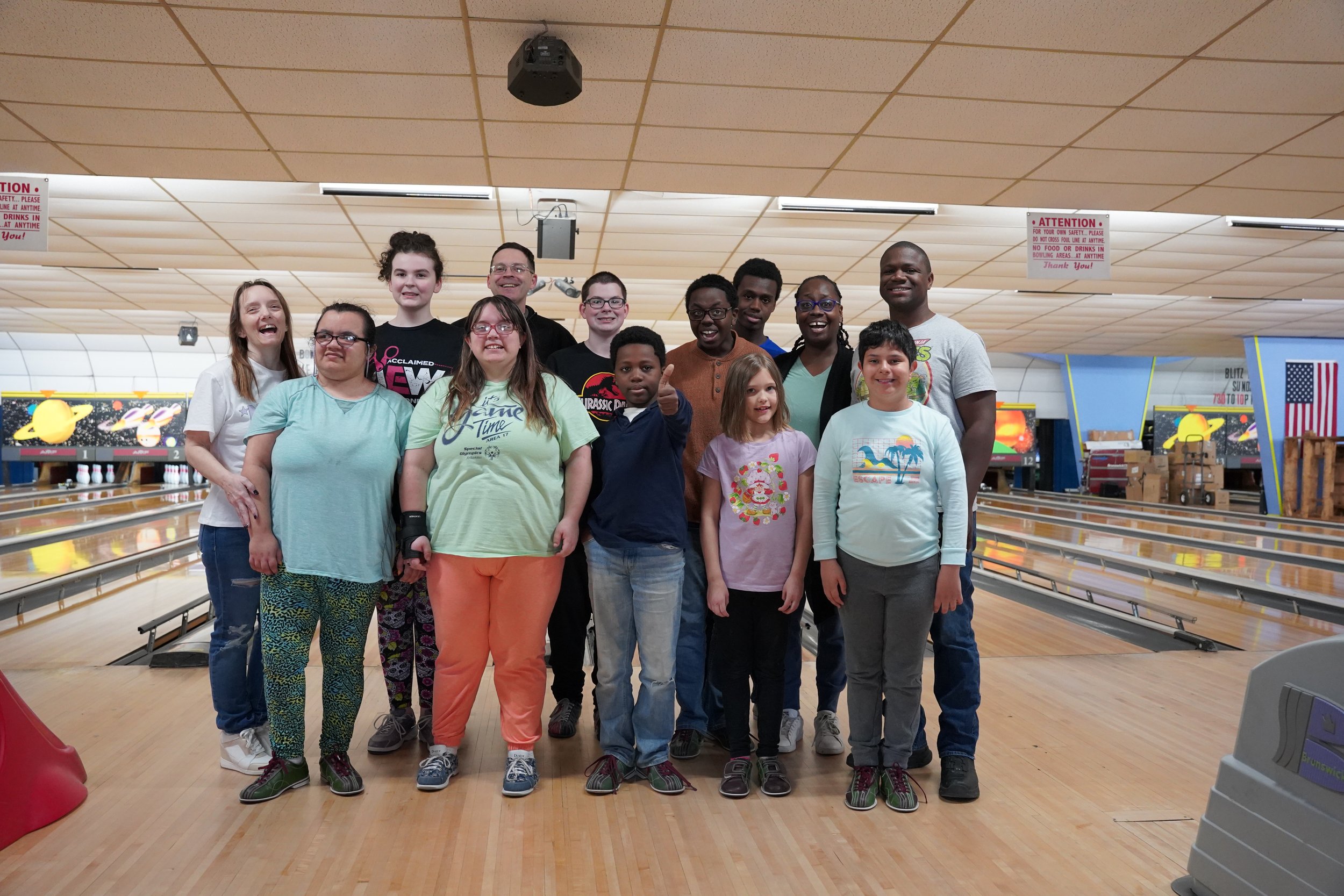 children and volunteers posing in a bowling alley